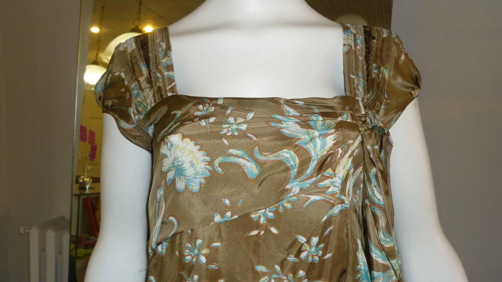 This silk floral pattern dress has never been worn and still has its tags. It looks like a very simple dress until you see details such as draped and pleated neckline with a side bow, and the pleat and sequin detail on the wide shoulder straps.