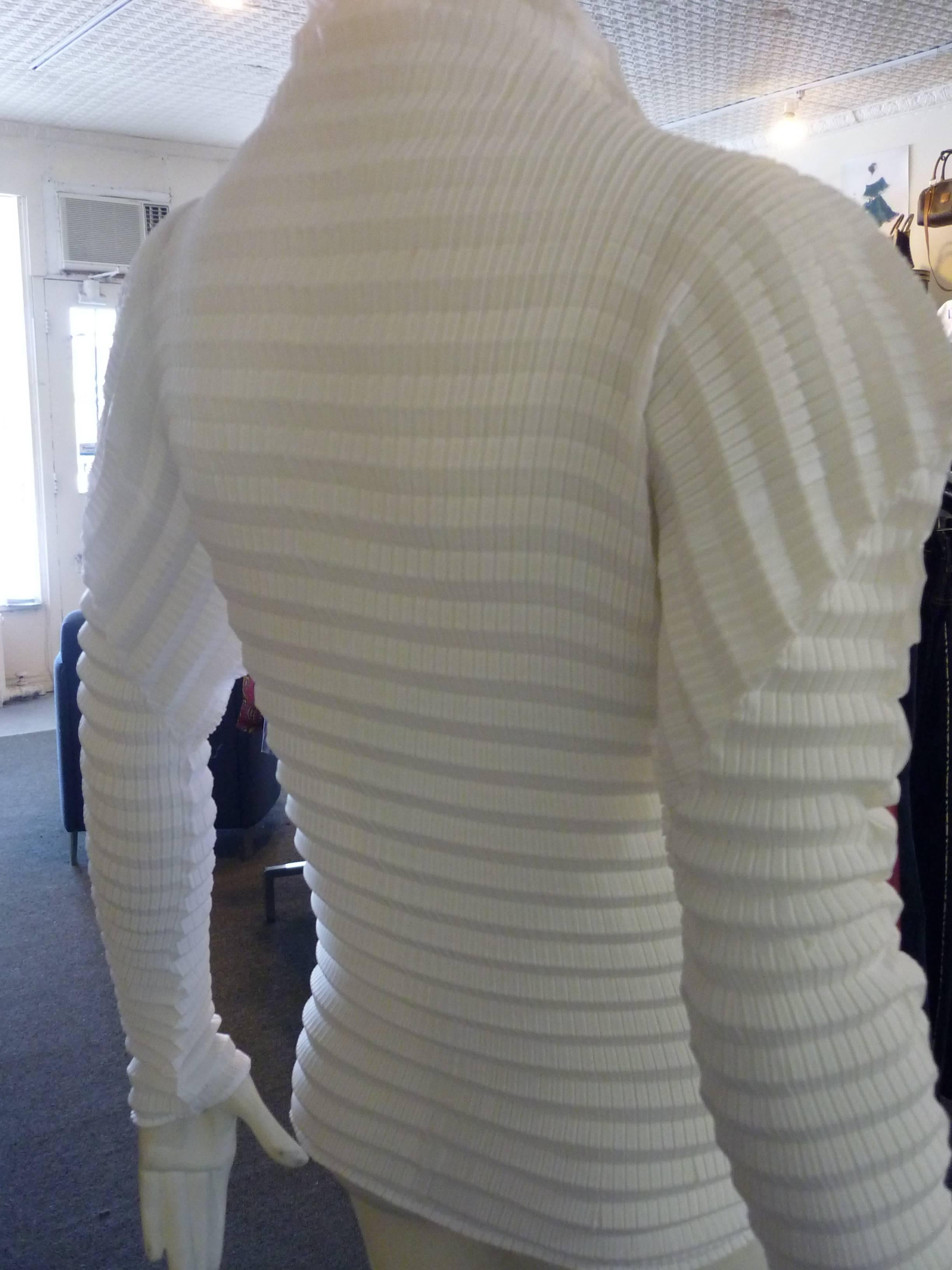 Horizontal accordion pleats; silver trim; high collar; side slits, and the versitility of this blouse (see pictures), make this a great addition to any wardrobe.

Please take into account that the blouse is stretchy. 