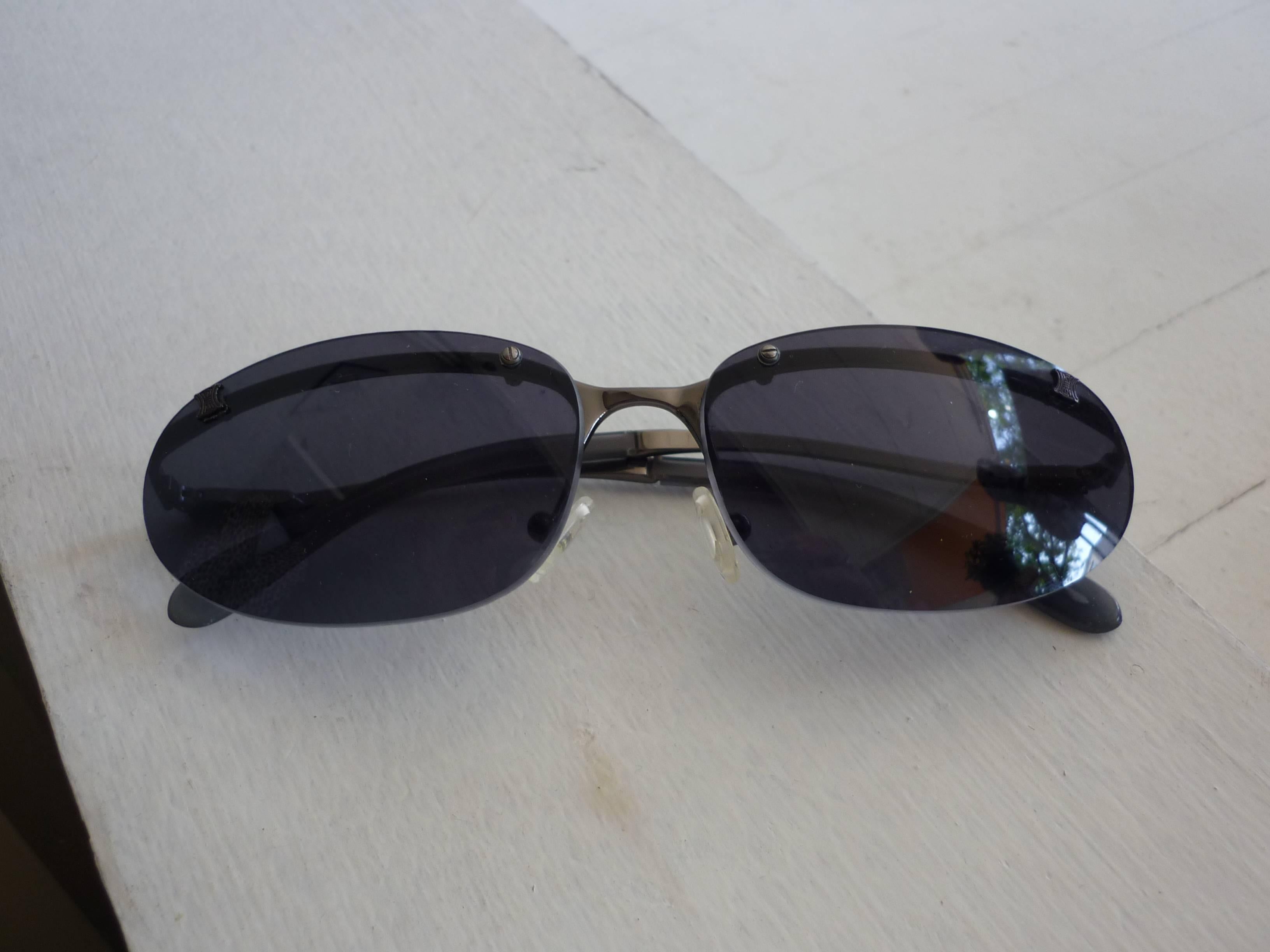 Lovely discontinued line, these Celine sunglasses look rimless as the rim is affixed to the inside. A silver raised Celine logo is found at the top of each lense, and incised on half of the arms in grey. The color of the lenses is grey.

The