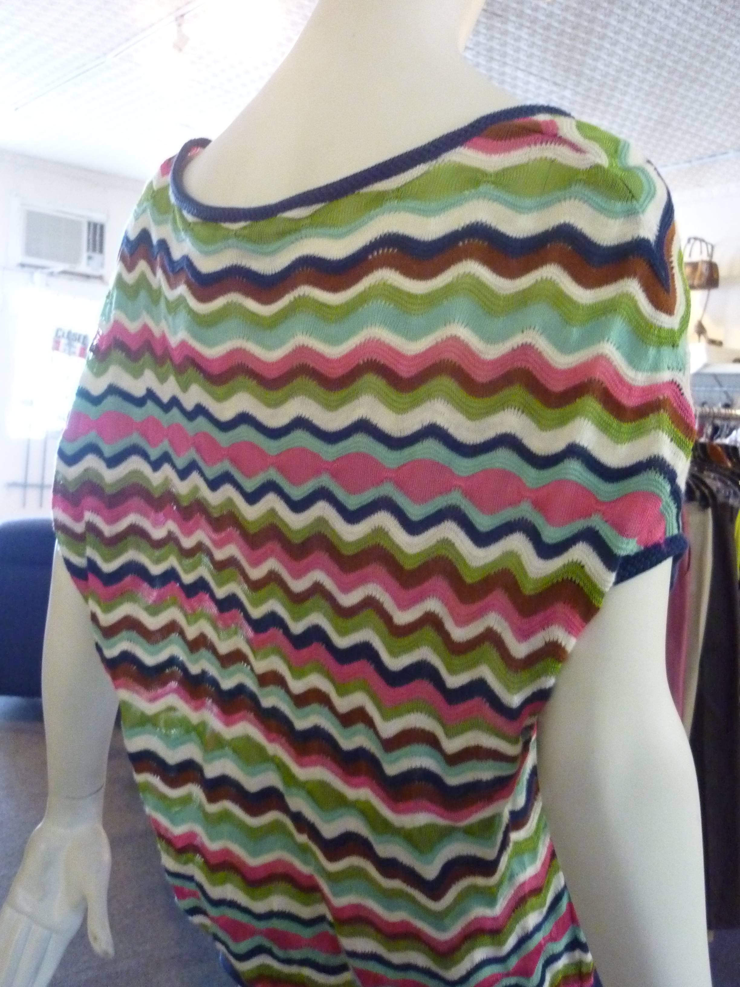 Wave, open weave pattern, bordered in navy blue, with pink, green,brown, white and blue being the predominant colors.

This top has dropped shoulders and a hint of sleeves.