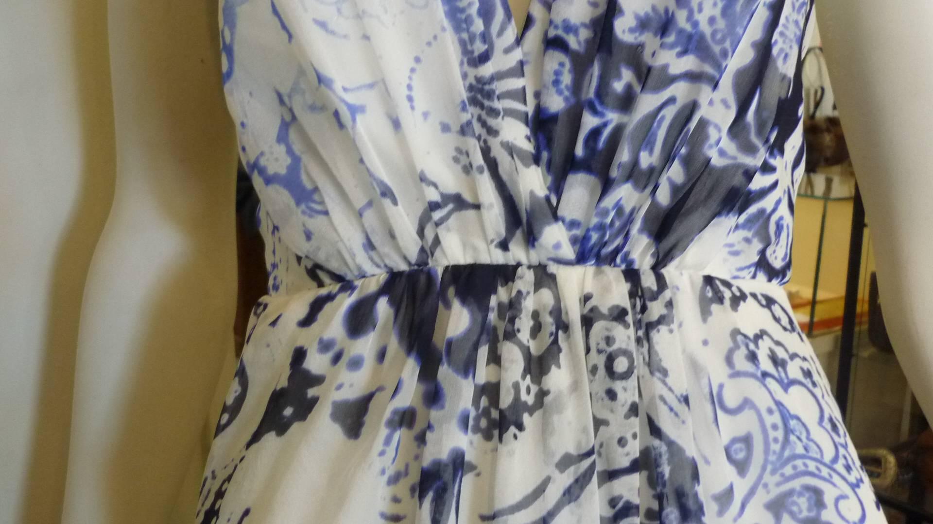 Silk chiffon (material tag missing) with a paisley floral print in white and blue, this dress has a lovely plunging neckline; a low back, and a longer hem in the back which forms a train. 