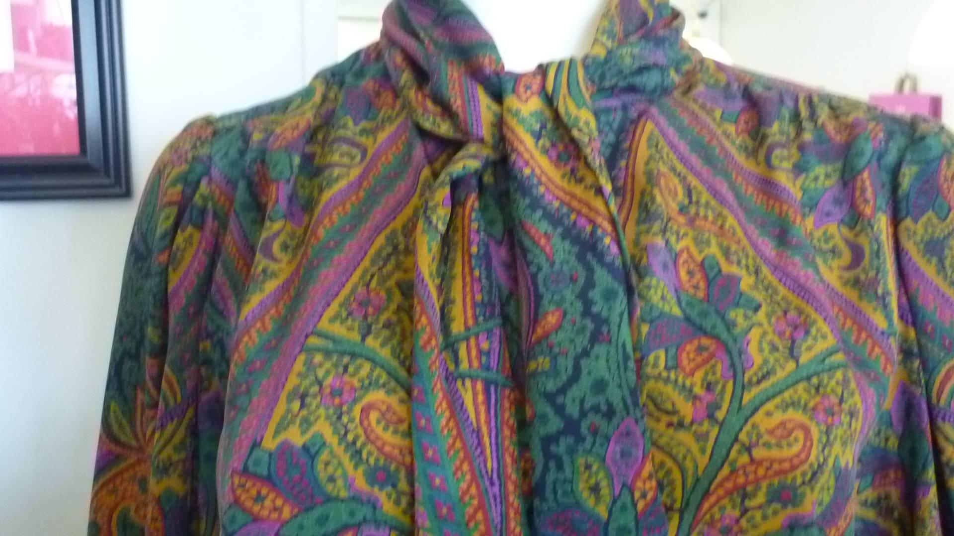 Bold paisley pattern of green, purple, orange and black, this blouse is typical of the 80s with an attached scarfand baloon sleeves.