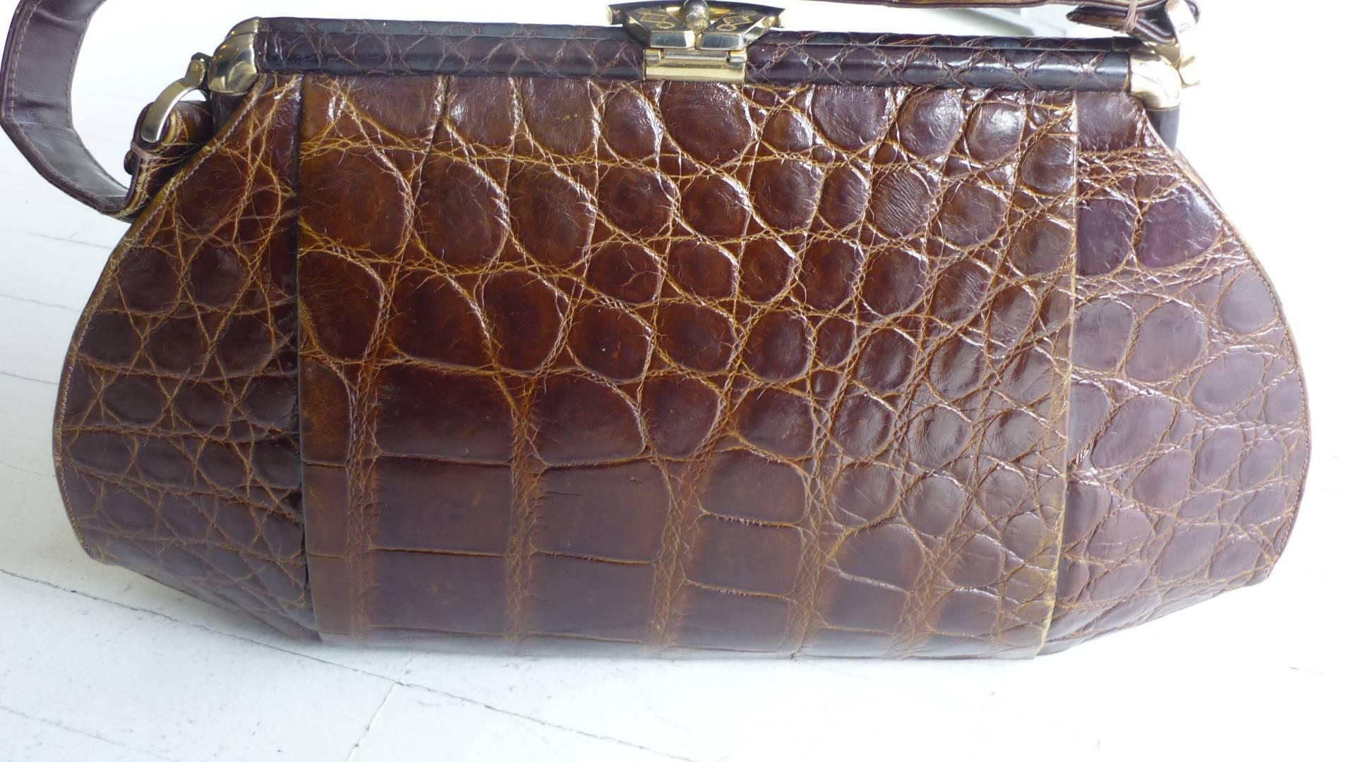 In magnificient condition for any age, this crocodile handbag has very nice hardware including the scythe-like closure mechanism; an unusual oblong shape; beige suede lining in amazing condition with one zippered pocket, and two large and one small