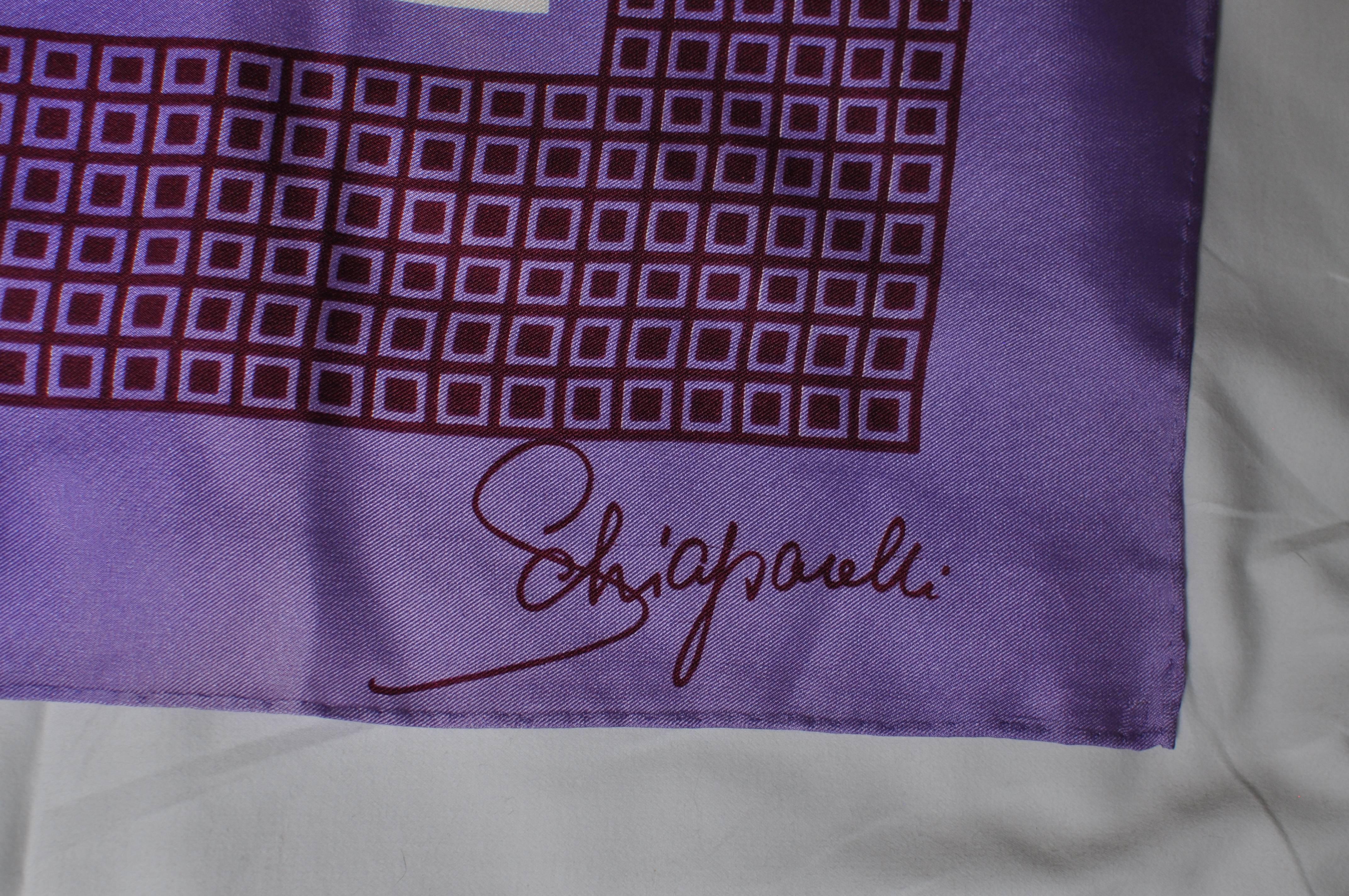 This signed Schiaparelli silk scarf has a square and diamond print in purples and off-white. There is some fading along some of the hem and one small pull, therefore I have marked it good.