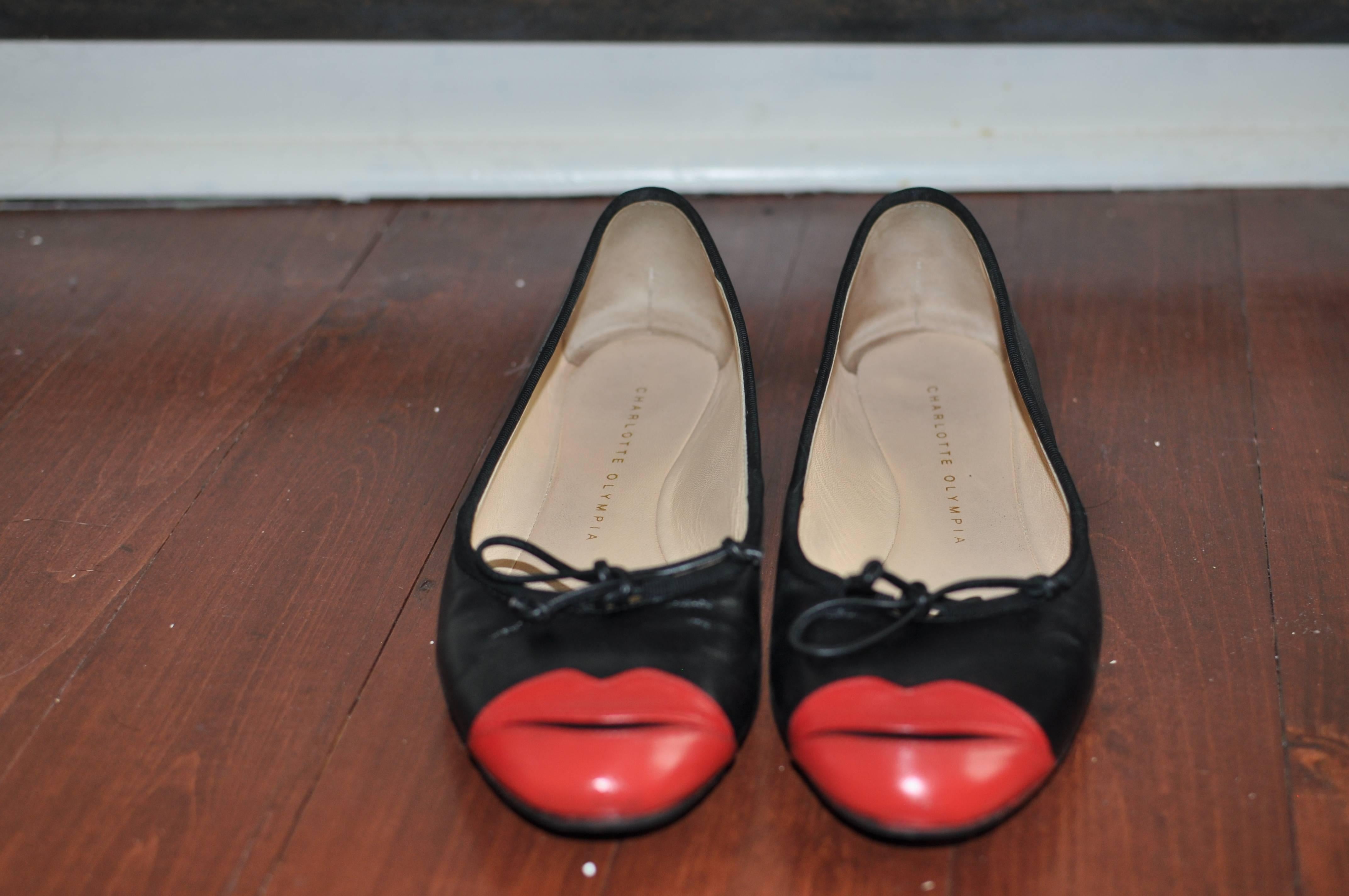 Black leather flats with red lip applique, these round toed shoes have .5