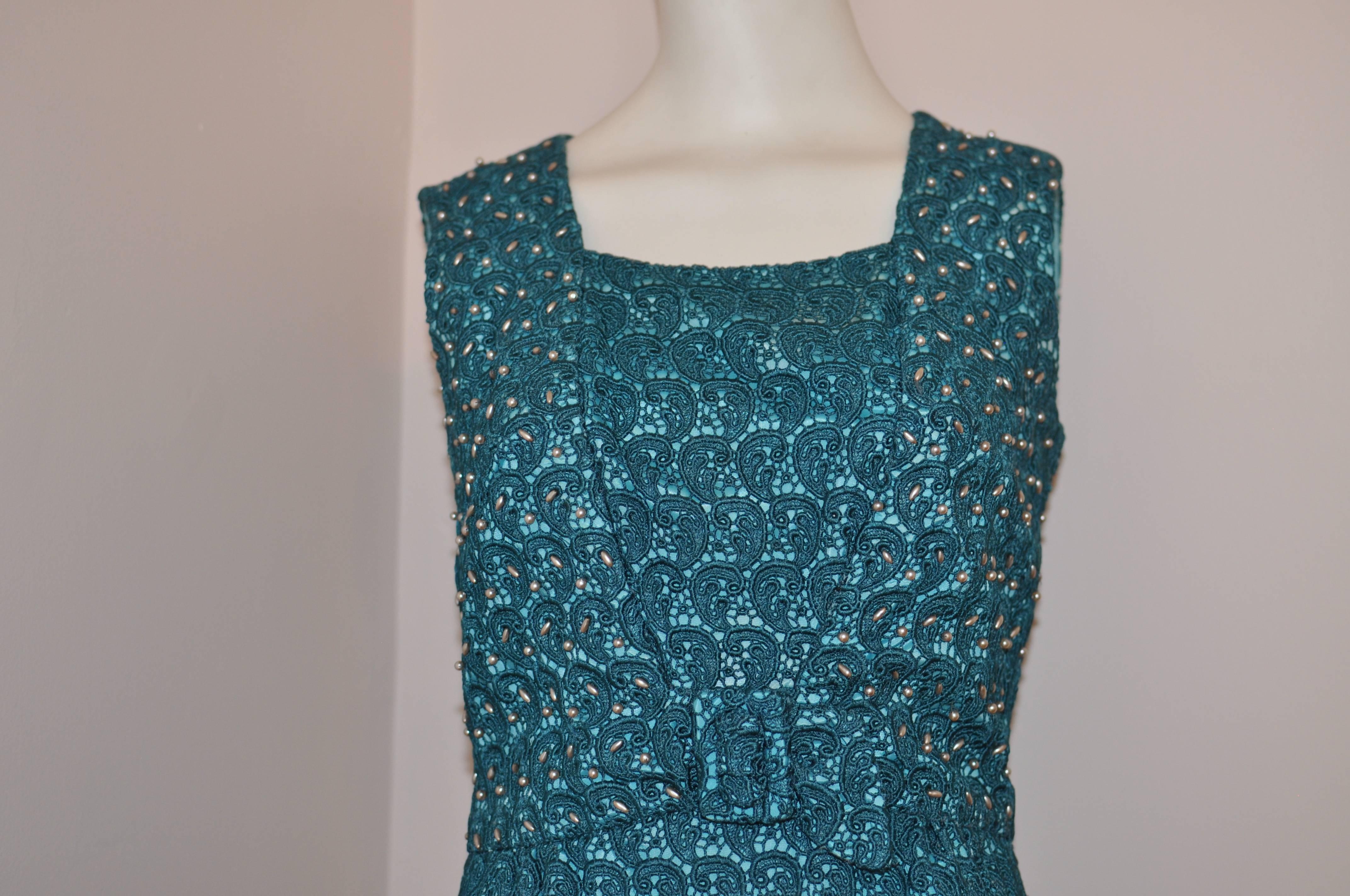 Wonderful example of a 1960s cocktaill dress with a paisley scalloped lace design an attached belt with buckle which can be adjusted, and see pearls at top and bottom.

This dress is in great condition with some discoloration on the lining.