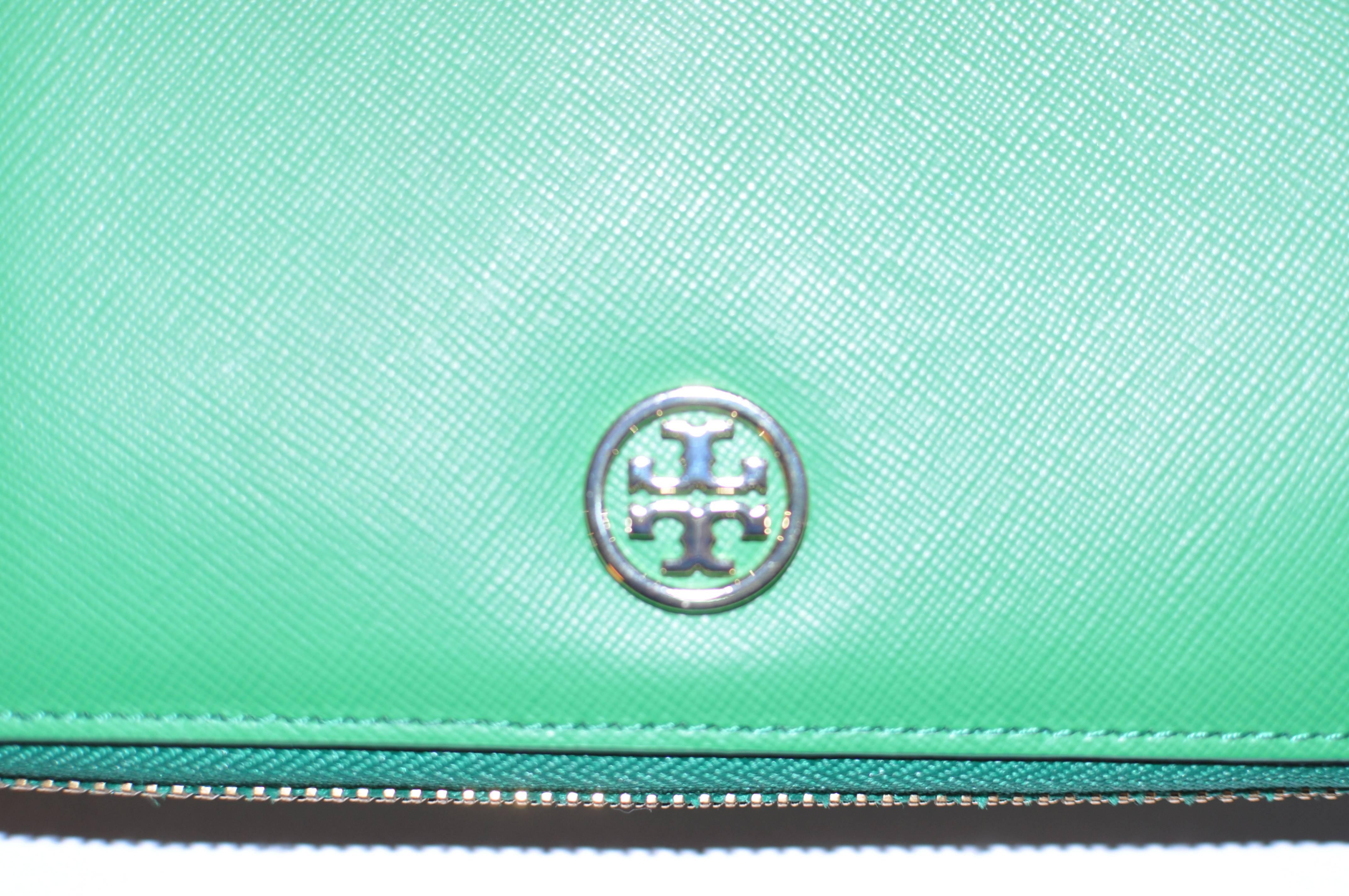 This is a never used wallet with a gold-tone Tory Burch logo, which zips on three sides with a gold-tone pull. Inside there are 8 slots for credit cards;two slots for paper money and a center zipped compartment.