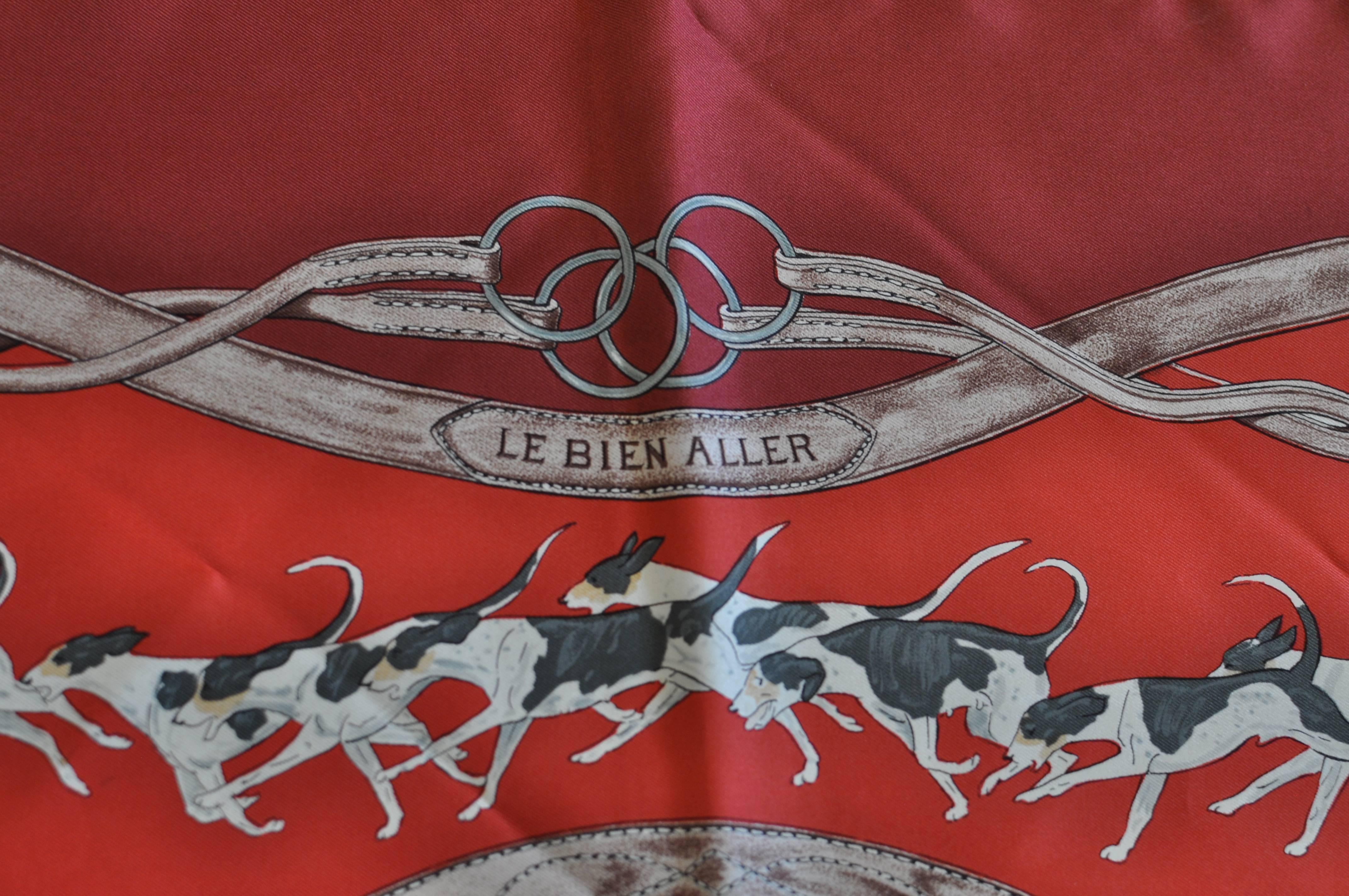 This is a scarf dedicated to the hunt with images of riders on horses, dogs, horns and assorted riding equipment. The background colors are burgundy and blue red with browns, beiges, and green. A lovely scarf in excellent condition for its age.