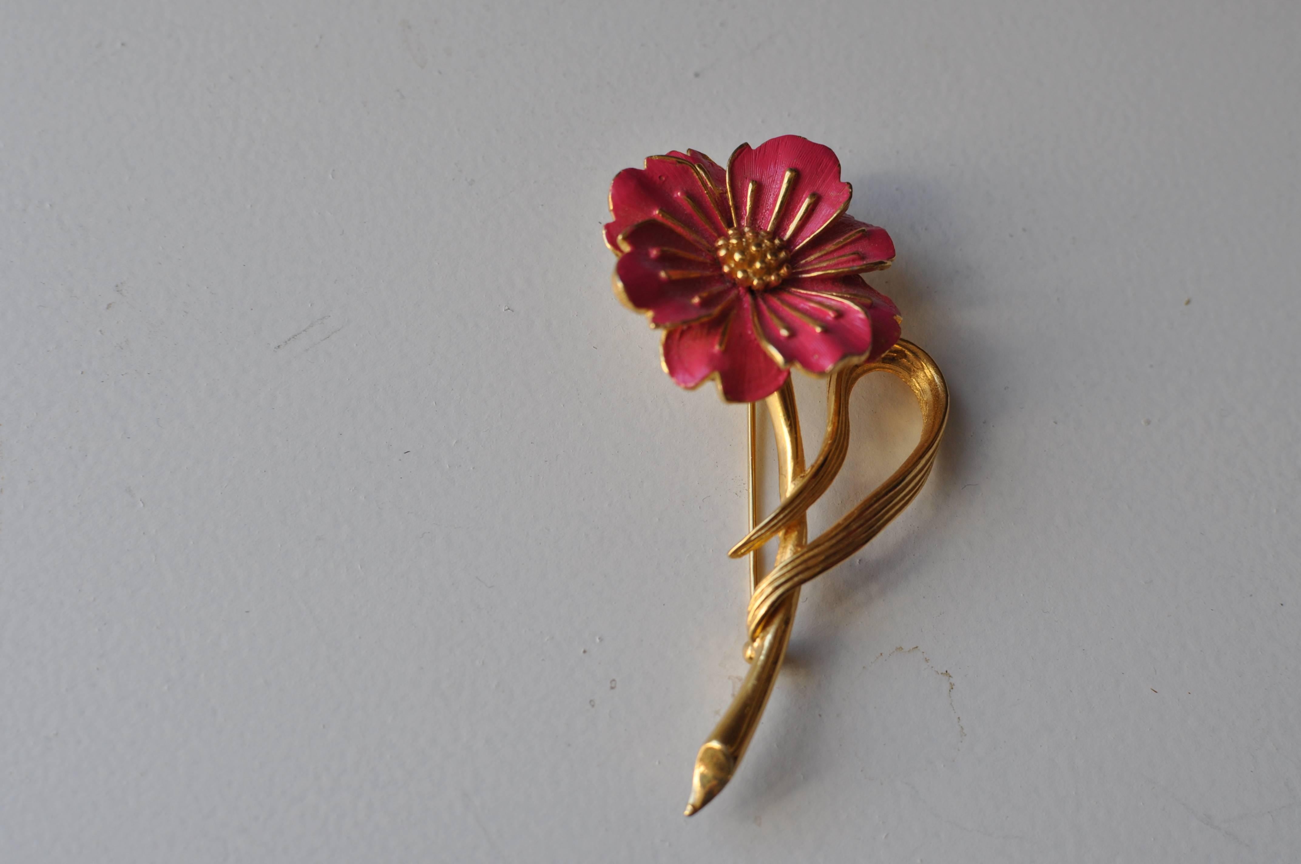Gold tone brooch with rose colored enameled flower and gold accents. The long stem and swirly leaf make this a very attractive brooch.

The brooch is signed Boucher and the serial # 8739P