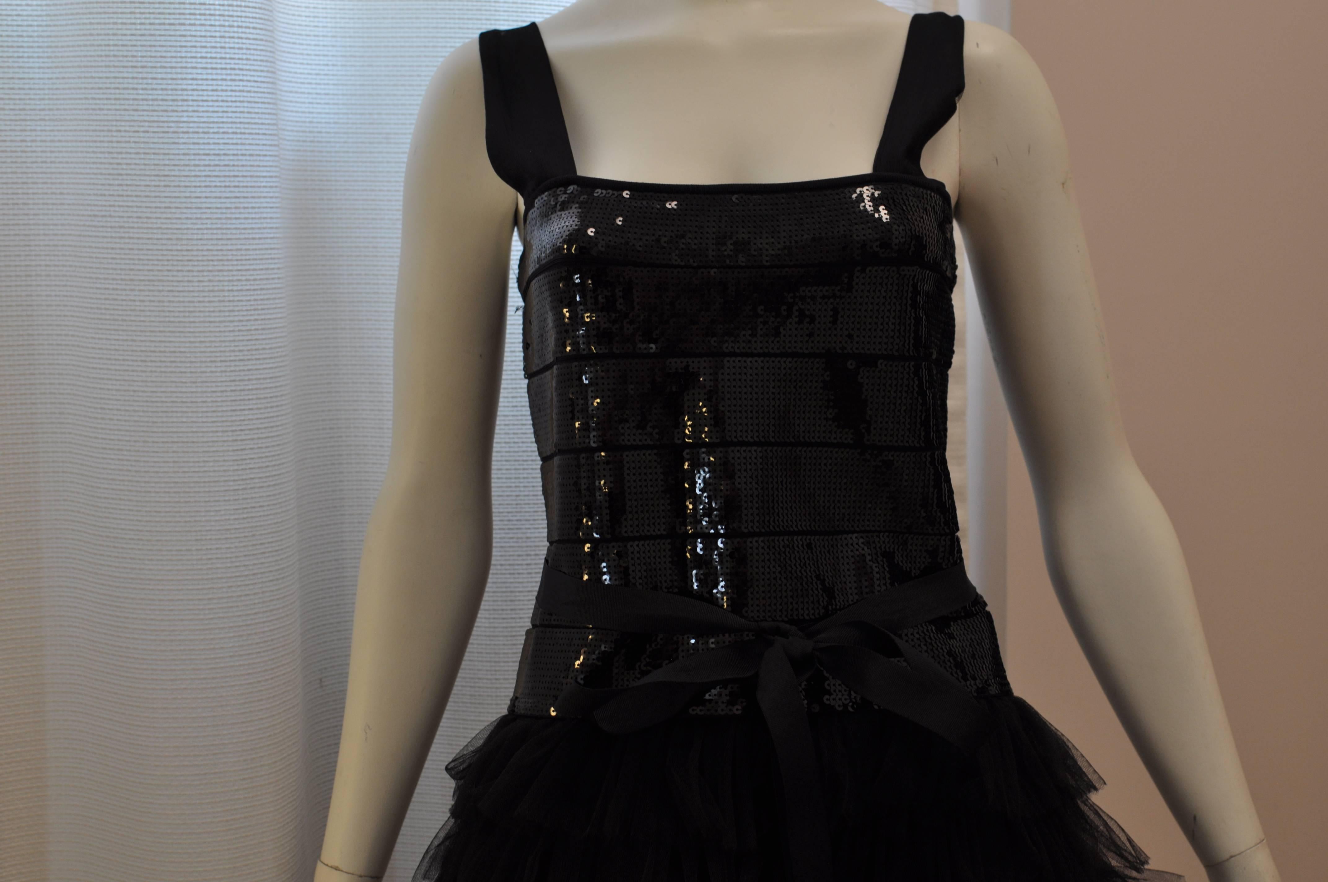 Striking dress with a sequin bodice and ruffled tulle skirt dress. There is a gros grain attached belt; a hidden zip closure center back and wide straps. The bodice is 90% rayon with rest nylon and spandex. The tulle skirt is made of polyester.
