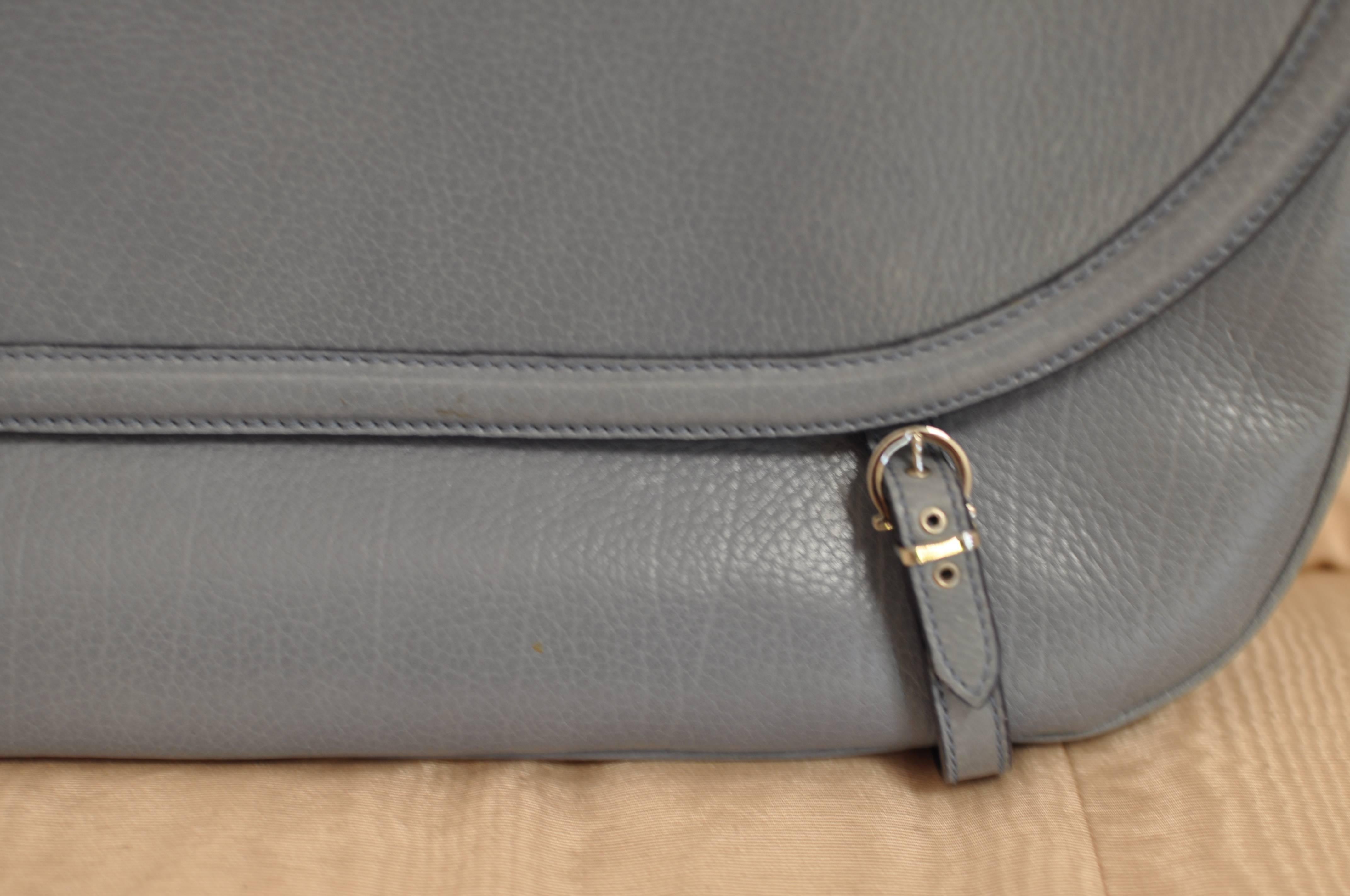 This is a very nice blue/grey grainy leather baguette handbag. Closure is by a flap snap and the belt details are for style purposes.

There one zipped pocket on the inside, and two compartments.  The 8