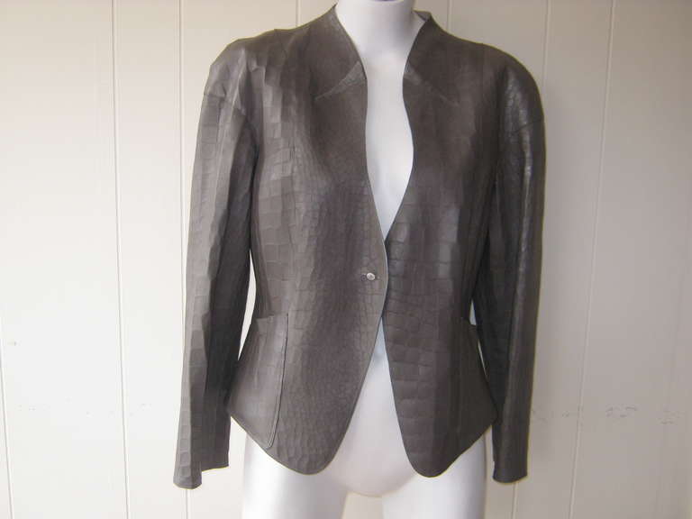 Beautiful grey leather jacket with a tulip shaped neckline adorned by a pleat on both sides which is replicated on slit but deep pockets, as well as the cuffs.

This jacket is very light weight and would make a great spring or fall  jacket.

The
