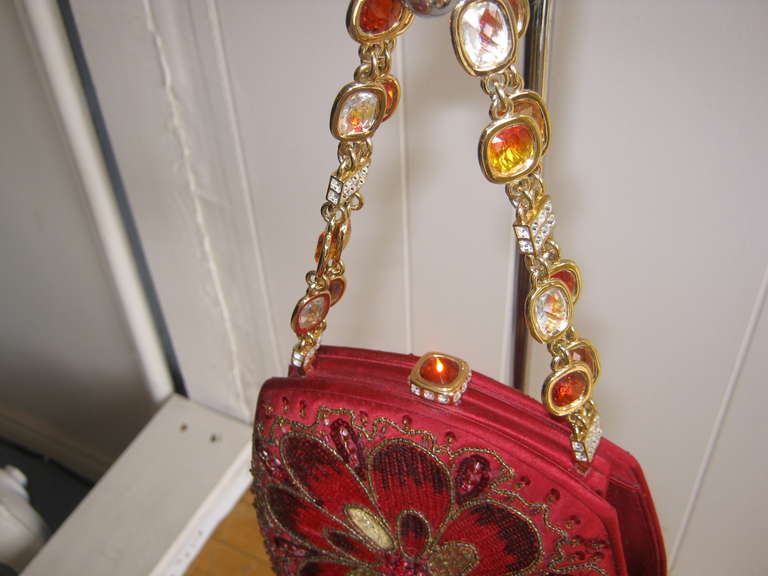 Is it a bag or a work of art? This stunning bag is highly collectible and the details  remarkable.

The bag is framed with red satin and the central motif is a floral design enhanced with amber, red and gold beading. It is framed at the top with