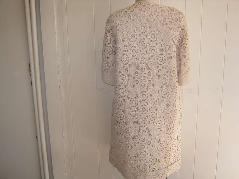 This hand made creation is absolutely fabulous and looks as new as the day it was made. The cream colored raffia coat is fully lined; has a V neckline; cuffed elbow length sleeves; scalloped slit pockets and closure is by one covered button and hook