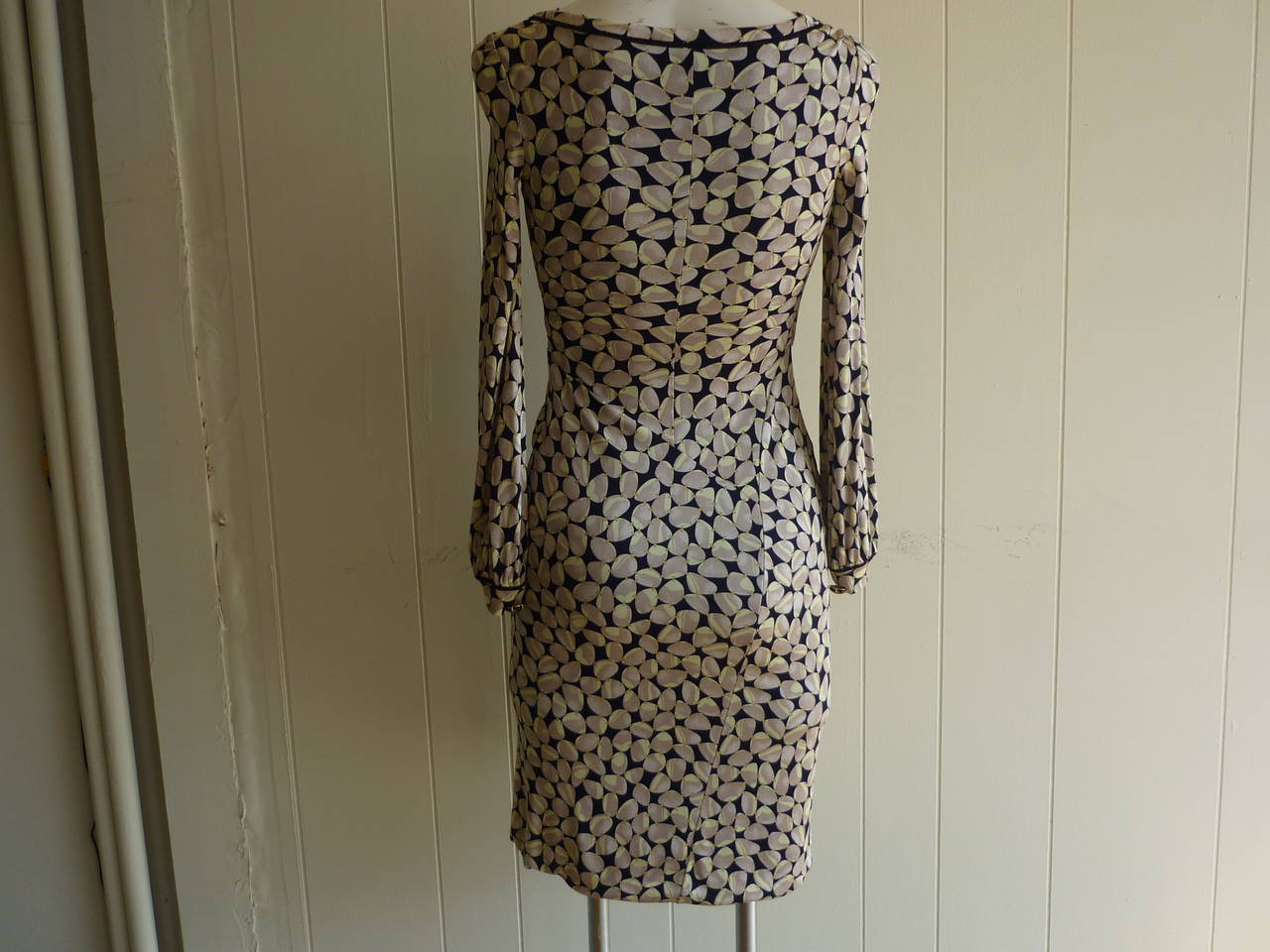 Delightful viscose dress with a silk lining in a button/cabochon design print. The neckline is slightly draped and the waistline gathered.

There is a black zig zag detail around the neckline as well as the cuffs which are adorned with beautiful