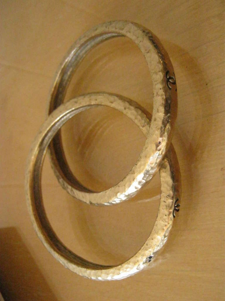 Fabulous and substantial Chanel bangles with clearly marked black CCs on two sides of each bangle, and a great texture.

They can be worn either dangling or higher on the arm. The opening is 2 5/8