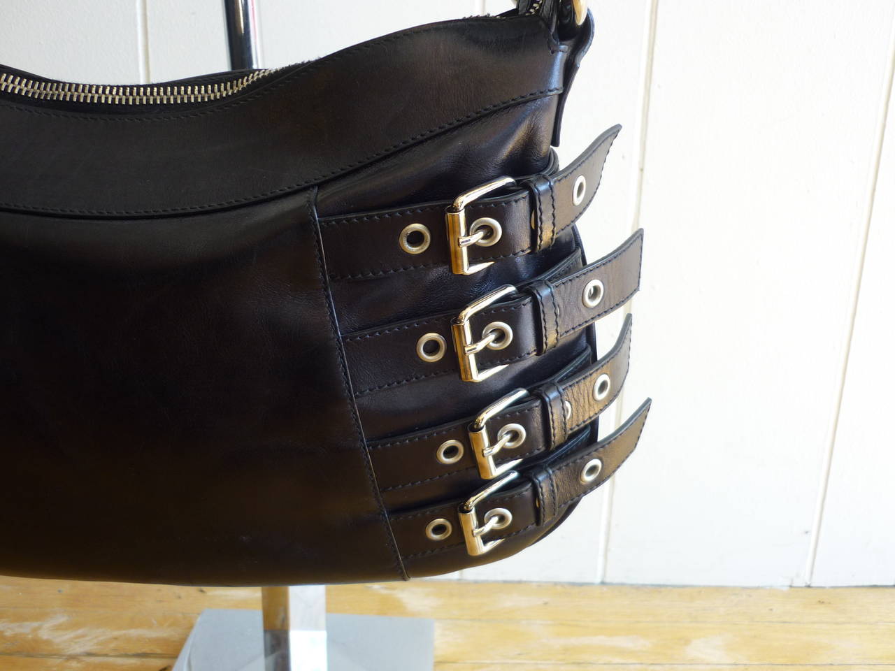 This handbag is repleat with silver tone hardware from the belt and buckle accents to the twin belt buckle shoulder straps which are adjustable. There is one interior zip pocket.

Mid-size handbag for any outfit from motorcycle gear to something