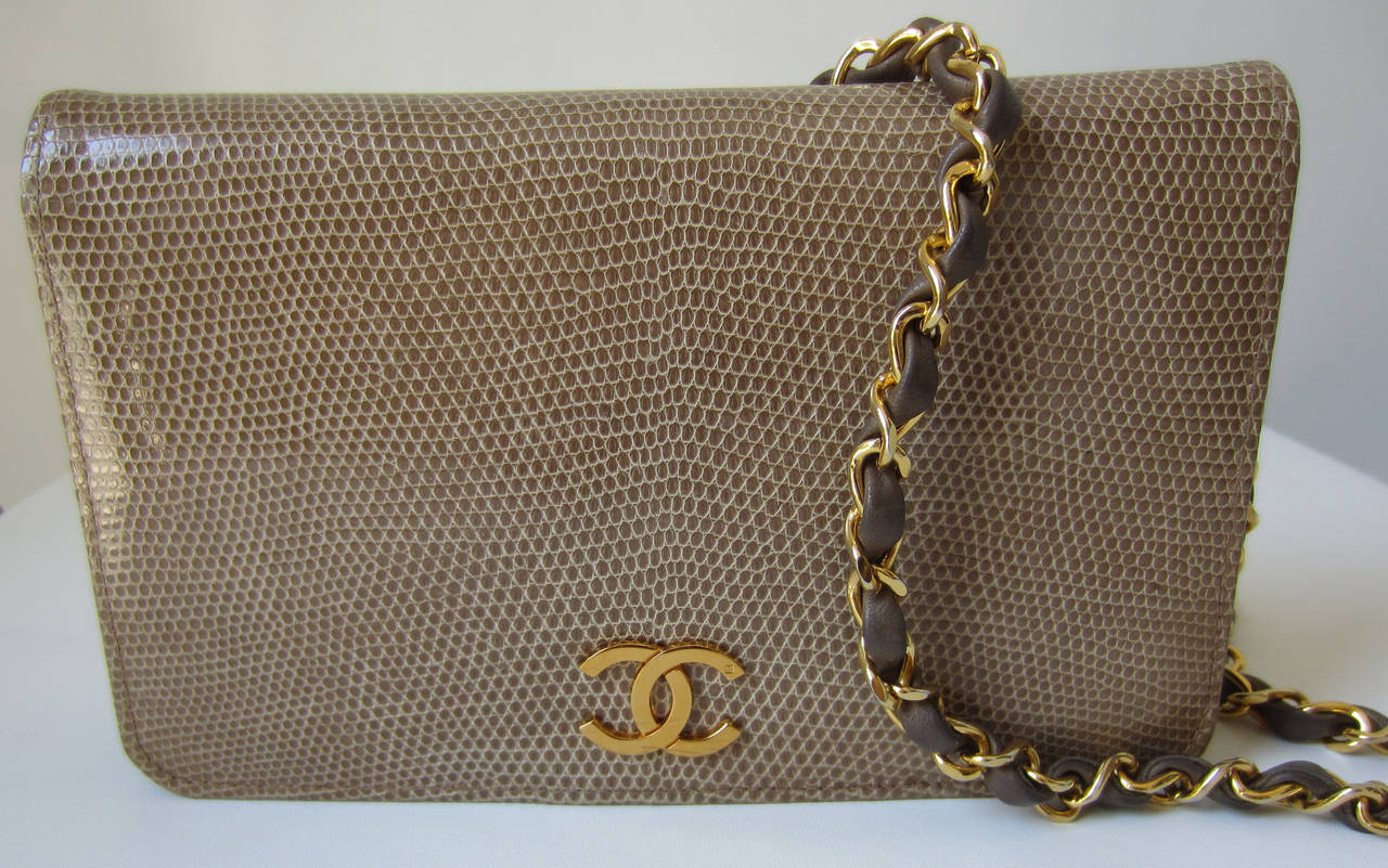 Elegant taupe lizard bag from Chanel Vintage featuring a hard flap closure with magnetic fastening and gold CC logo.
Featuring a lizard and gold chain shoulderstrap.