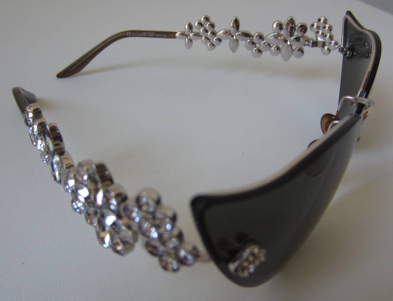 This is an authentic pair of Louis Vuitton Crystal Fleur Cat Eye sunglasses nr. 501 of 1000 produced world wide.
These stylish glasses have classic cat eye rims with lenses that are a shade of silver.
The arms have all the Louis Vuitton monogram