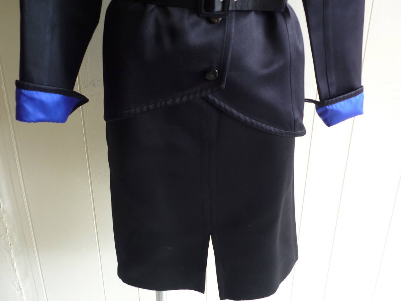 Great example of an Yves Saint Laurent RG 1980s piece: big shoulders; Russian style side closure and bonded royal blue lining. The jacket is belted and the skirt is straight with a slit in the middle front. There is some slight wear to the fabric.