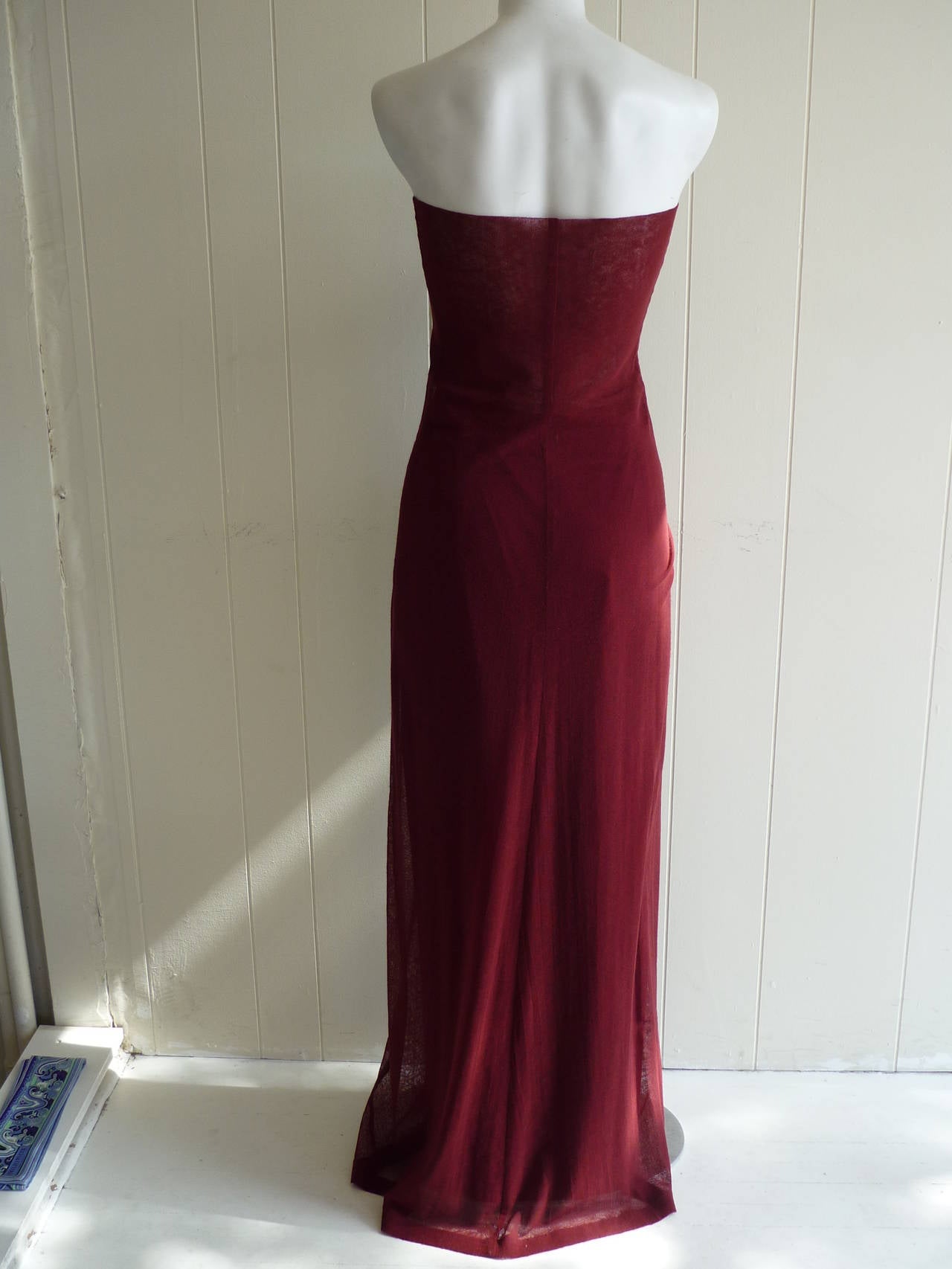 So feminine and elegant with a touch of risque, the sheer mesh maxi dress folds at the top to afford more coverage, but leaves a strip of see through around the top of the stomach. The color of the two-piece outfit is burgundy.