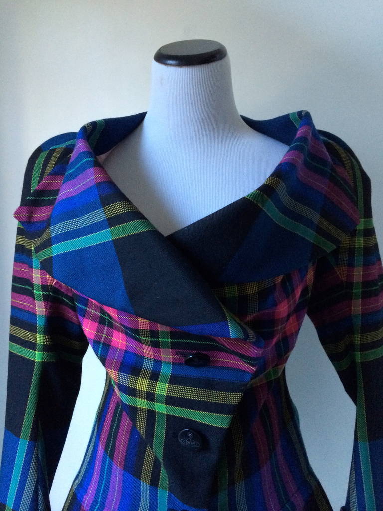 From the Queen of Plaids this wonderful Blazer is a true gem. Its precise tailoring and the clever use of tartan fabric gives this blazer a look that is rare to achieve . The waist is very fitted with an asymmetrical closure.
In the back you have a