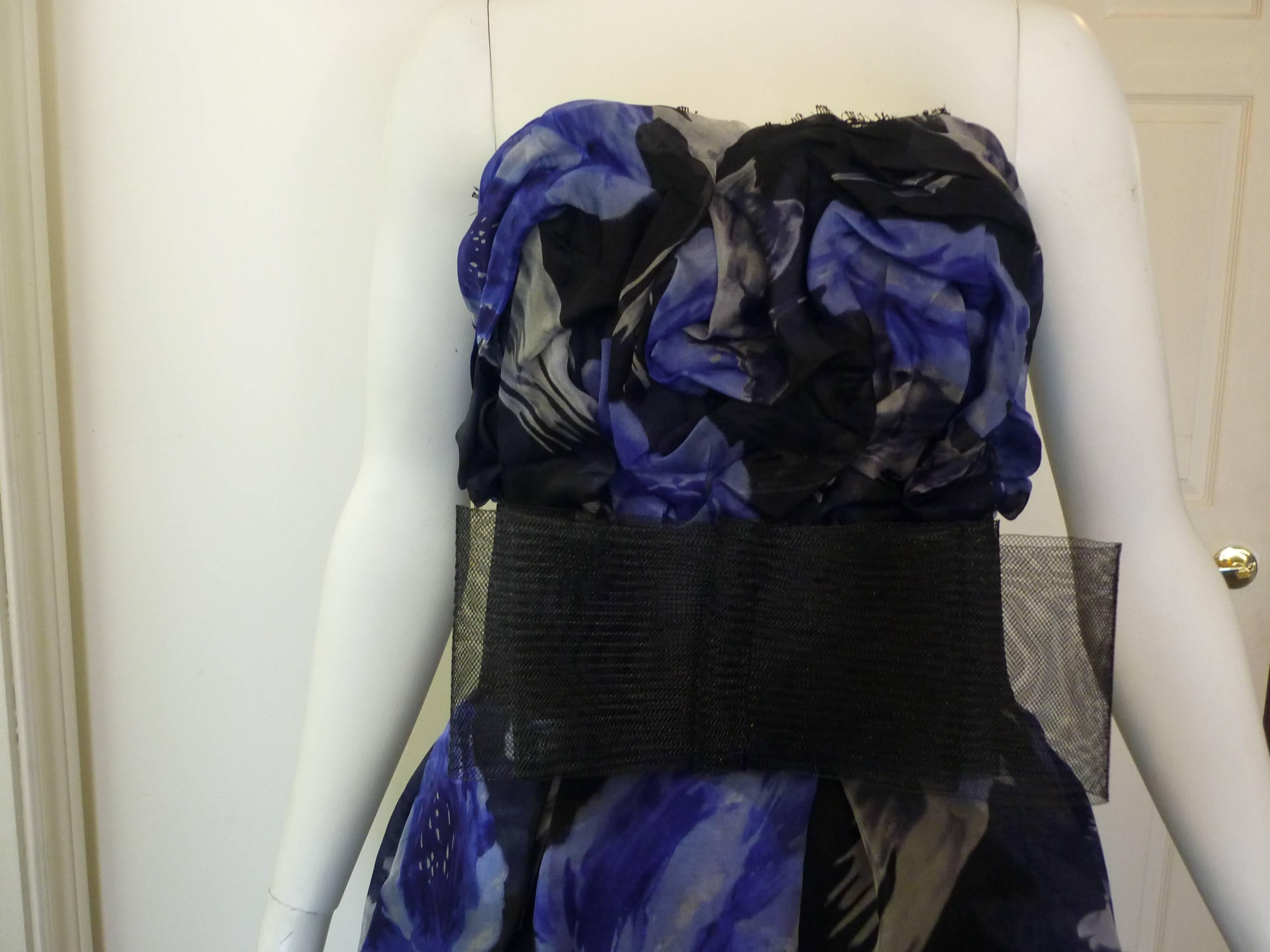 Blue, black and white Marchesa Notte silk floral print, this dress is strapless with a sweatheart neck,  and has boning at the bodice. There is also a mesh bow at the waist, and lace trim at the top and bottom. Closure is by way of a back invisible