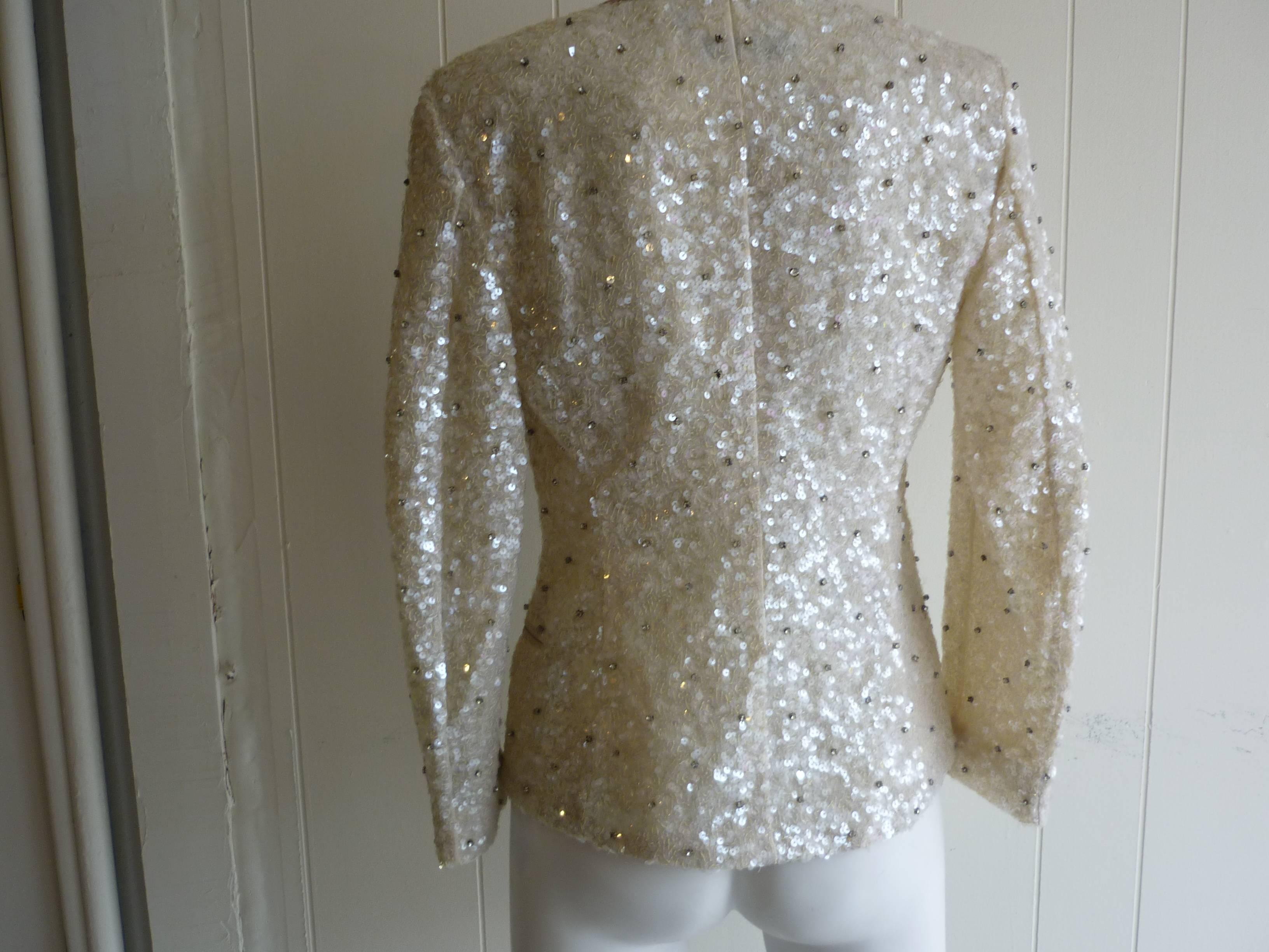This jacket will enliven any outfit! It is silk embellished with sequins and brilliants; has a georgette lining; two fake satin edged pockets on the front; a satin lapel and closure is by two satin ribbons.