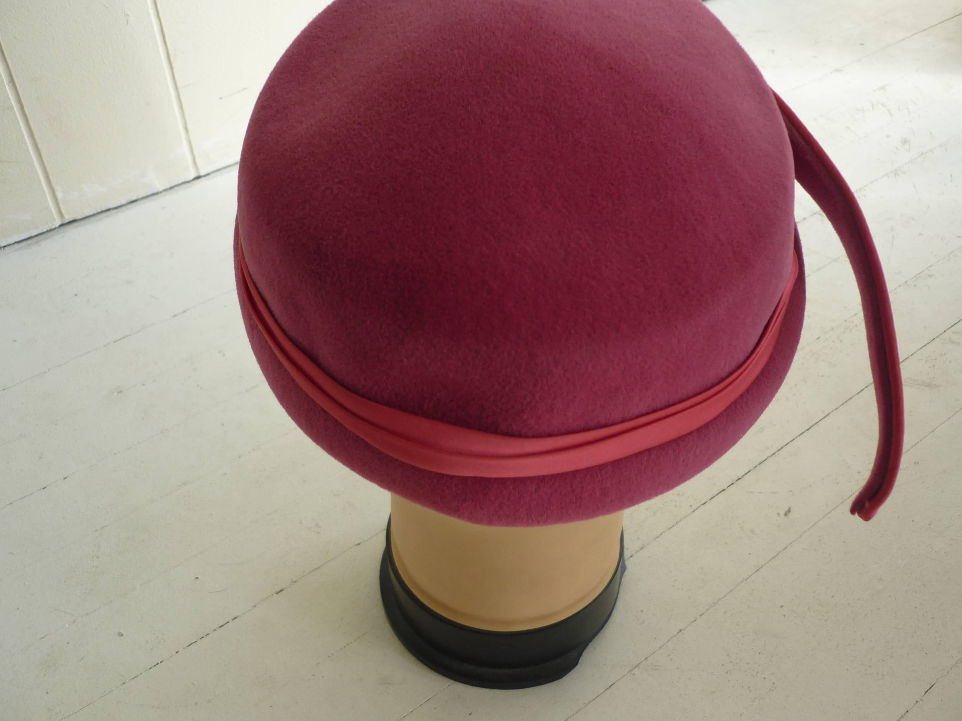 Made of felt, trimmed with satin, with a featherlike adornment, this hat fits snugly on your head.

The underside of the hat has a serpentine silver and gros grain trim.

The hat was made in Italy.