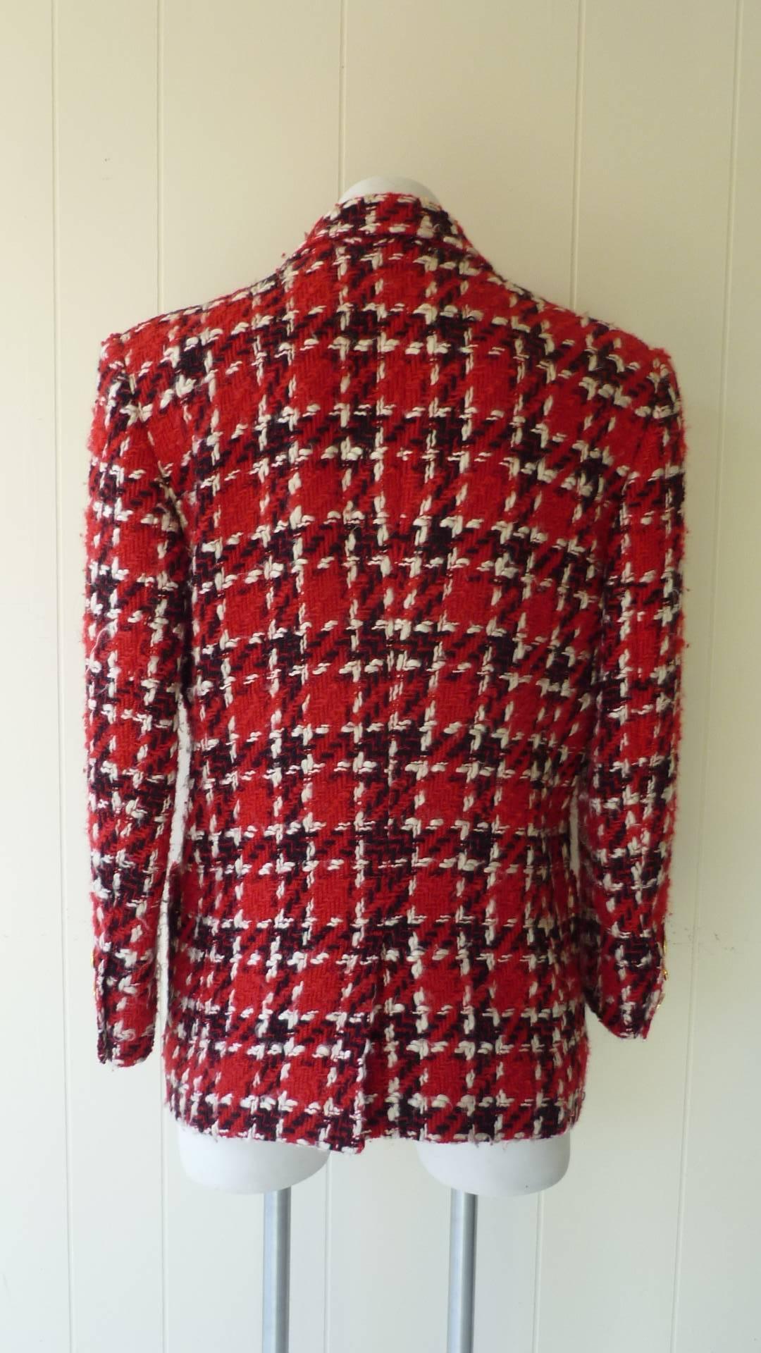 This is a traditional 1980s tweed jacket with a red, white and black weave. There are four front pockets, two with Rue Cambon buttons; a vent to the back; three Rue Cambon buttons on each sleeve, and a lapel collar.