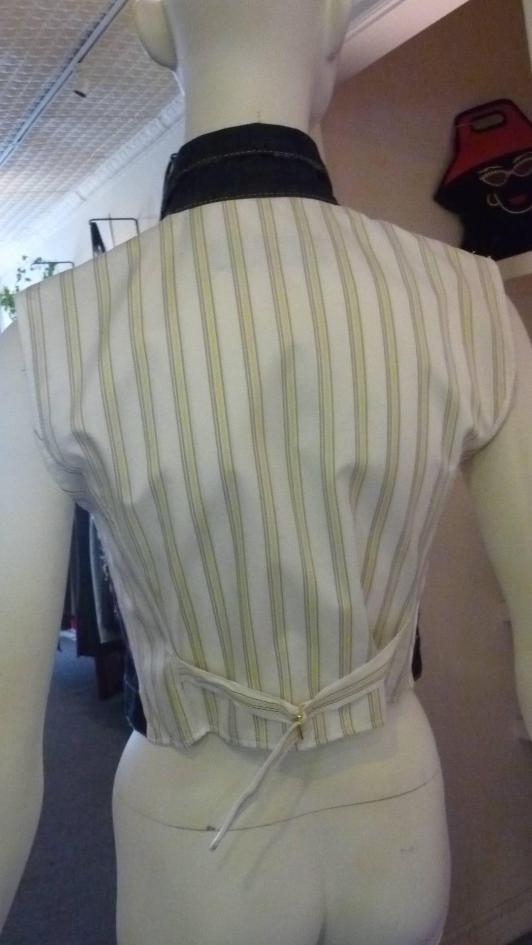 A blue tretch cotton front with a classic collar; two buttoned chest pockets; front button fastening, and stitching details. The back is a contrast stripped satiny cotton with a half belt fastening.