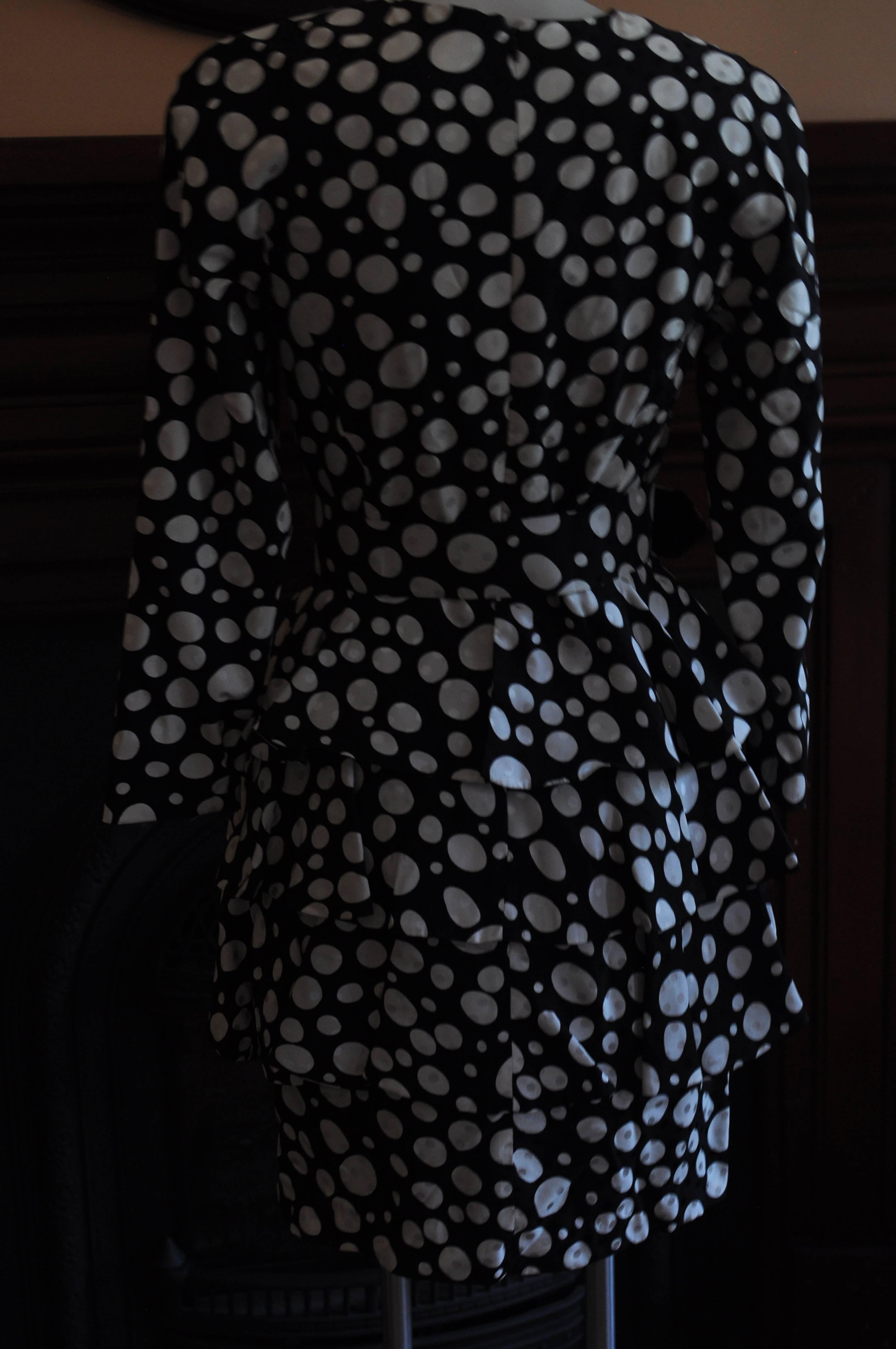 Perfect cocktail dress! This Arnold Scaasi silk dress is tiered; has a round collar; a wide belt and a polka dot pattern of different sizes which also superimposed.