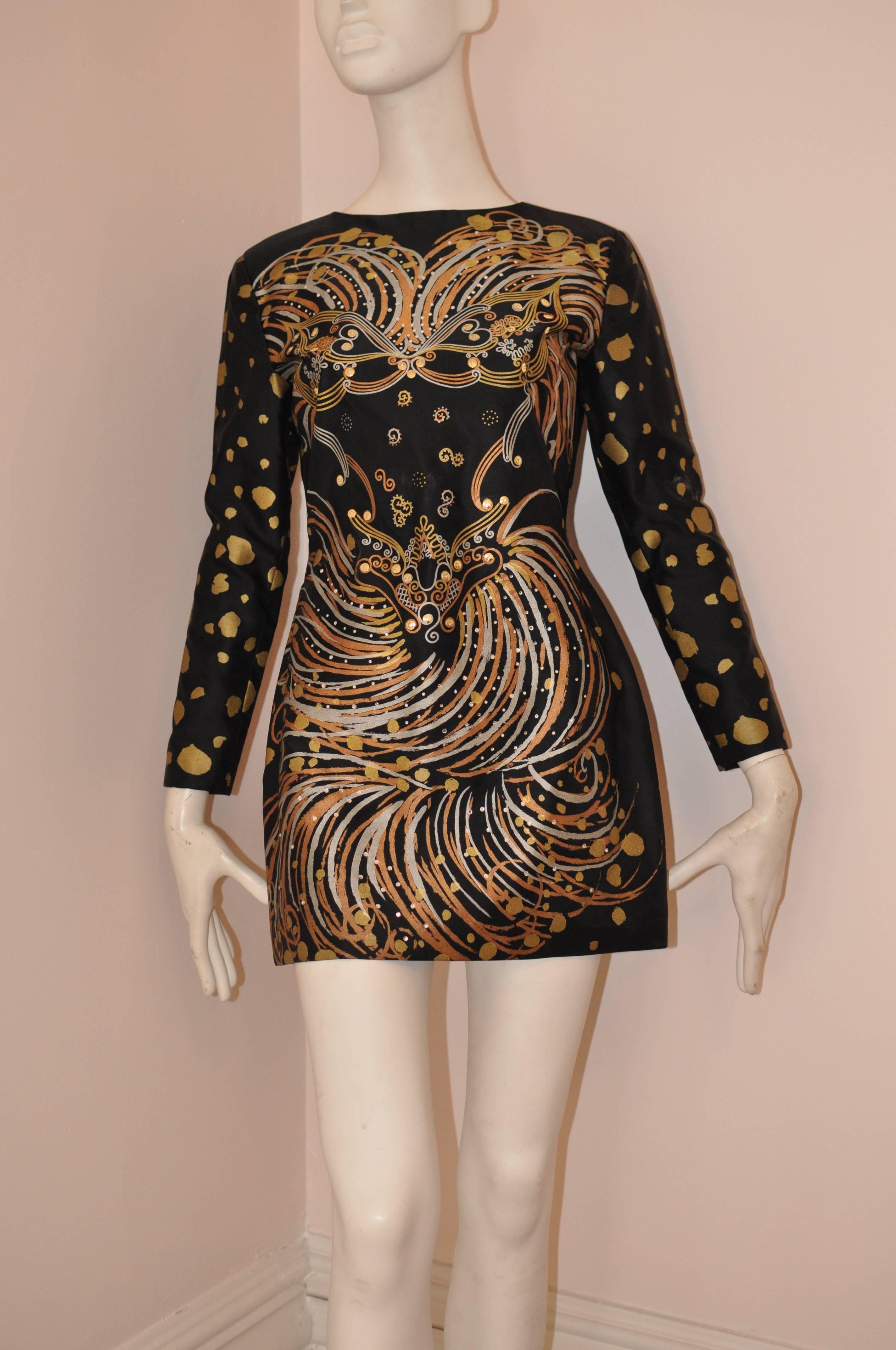 Great example of Zandra Rhodes' work, this acetate mini dress/tunic has hand painted designs in gold, bronze and silver with gold metallic accent and diamante stones.

This dress also has a nice pleating detail in the back, and a hidden zipper