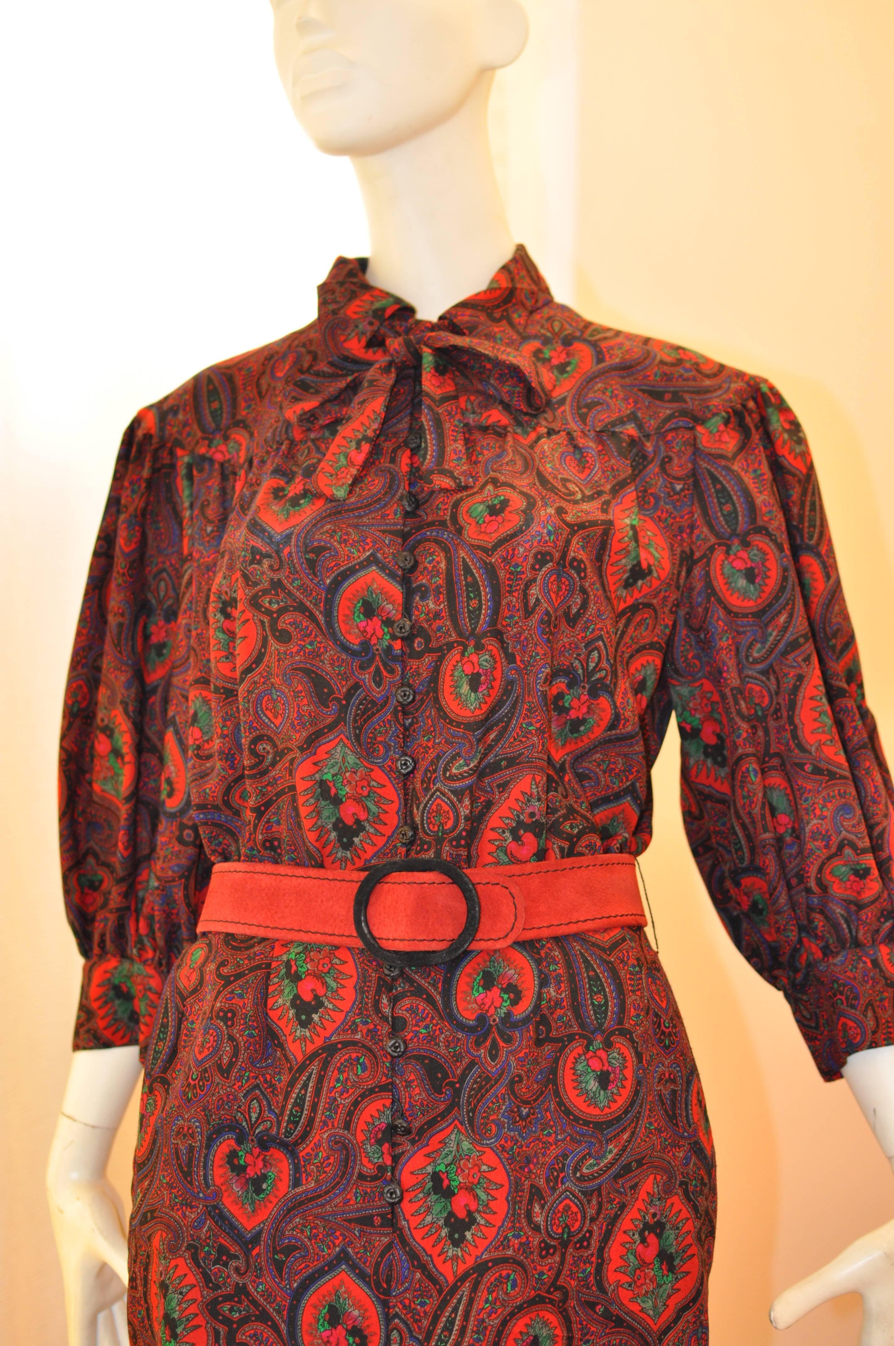 I believe this dress is Scherrer's 1990 collection. It is made of a light wool weave, and the colours are red, green and black, with a red suede belt. The balloon sleeves have two rose buttons at the cuff, which is also seen on the front of the