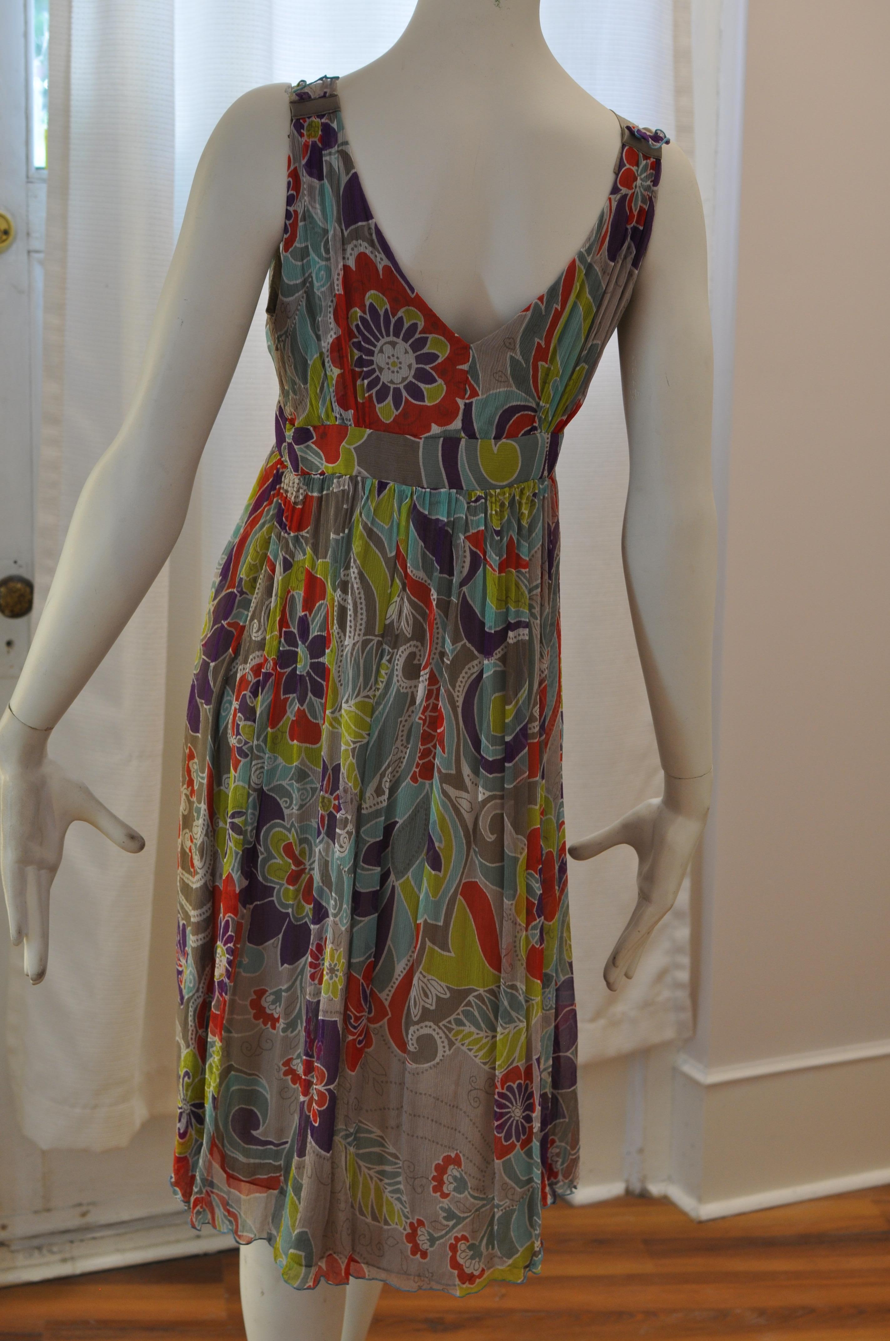 Lovely summer dress with a bold and colorful floral pattern. Nice pleated detail above the bust line; band on the waist line and interesting strap detail.

Closure is by a side zipper.

This dress is in excellent condition.