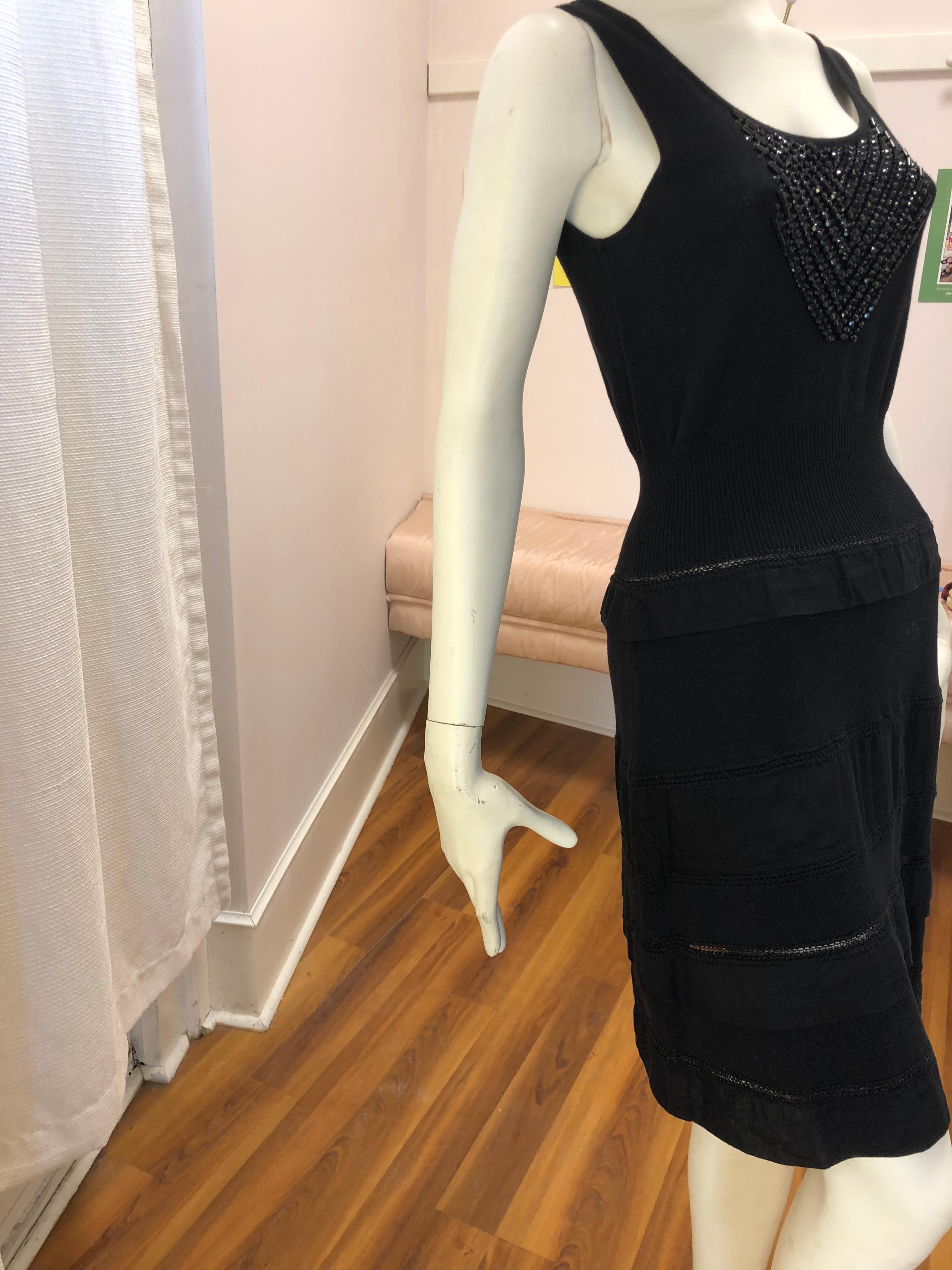 The sleeveless dress has an arrow pattern of black beads on the chest a ribbed expandable waist; three strips of metallic bands as well as a number of flat frills. Would make a great cocktail or evening dinner dress.