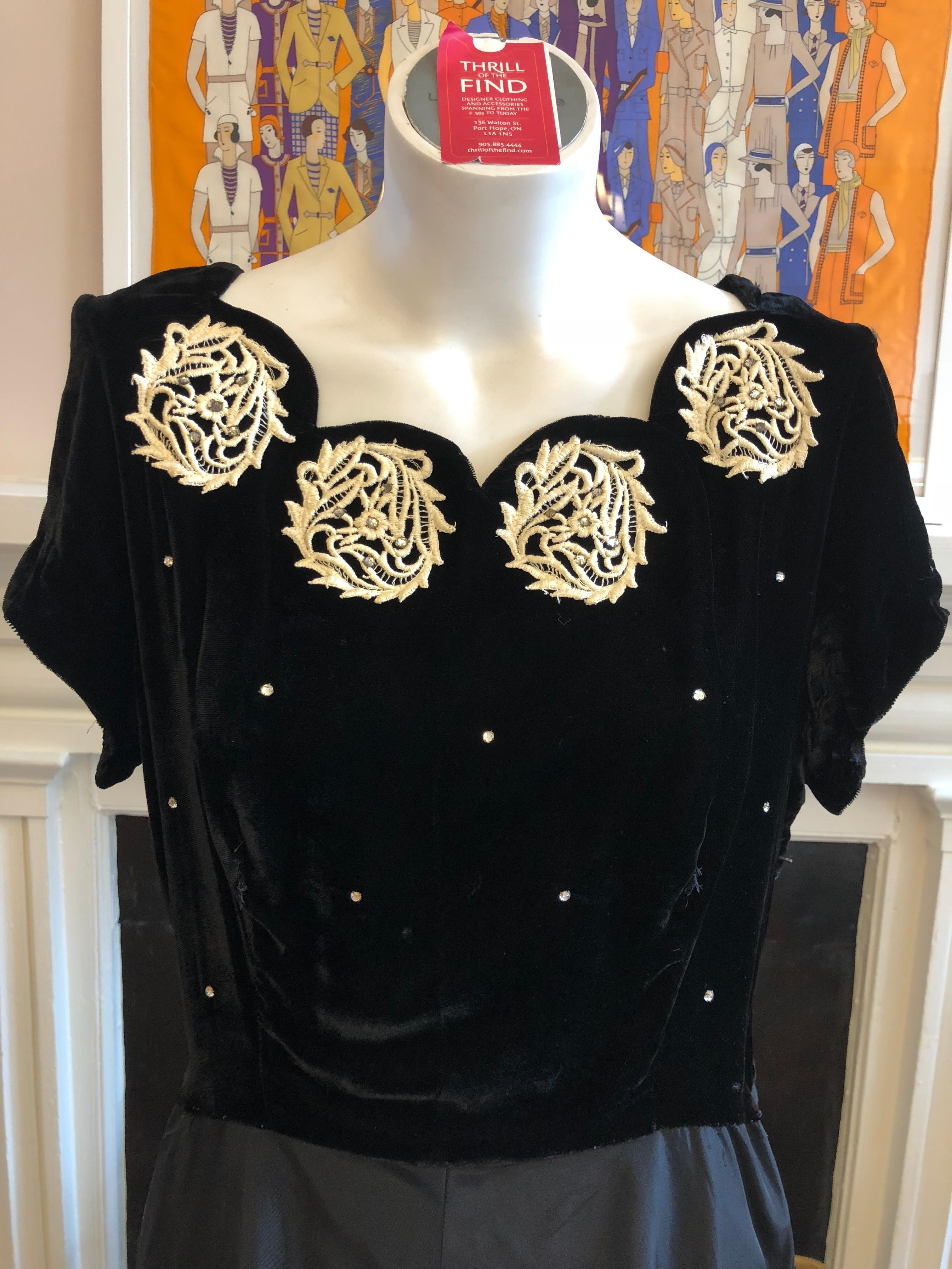 This tailored dress is in great condition for its age. The upper part is velvet embellished with embroidery and has a scalloped neckline and diamente. The rayon skirt has a shine and upon close inspection some slight discoloration.