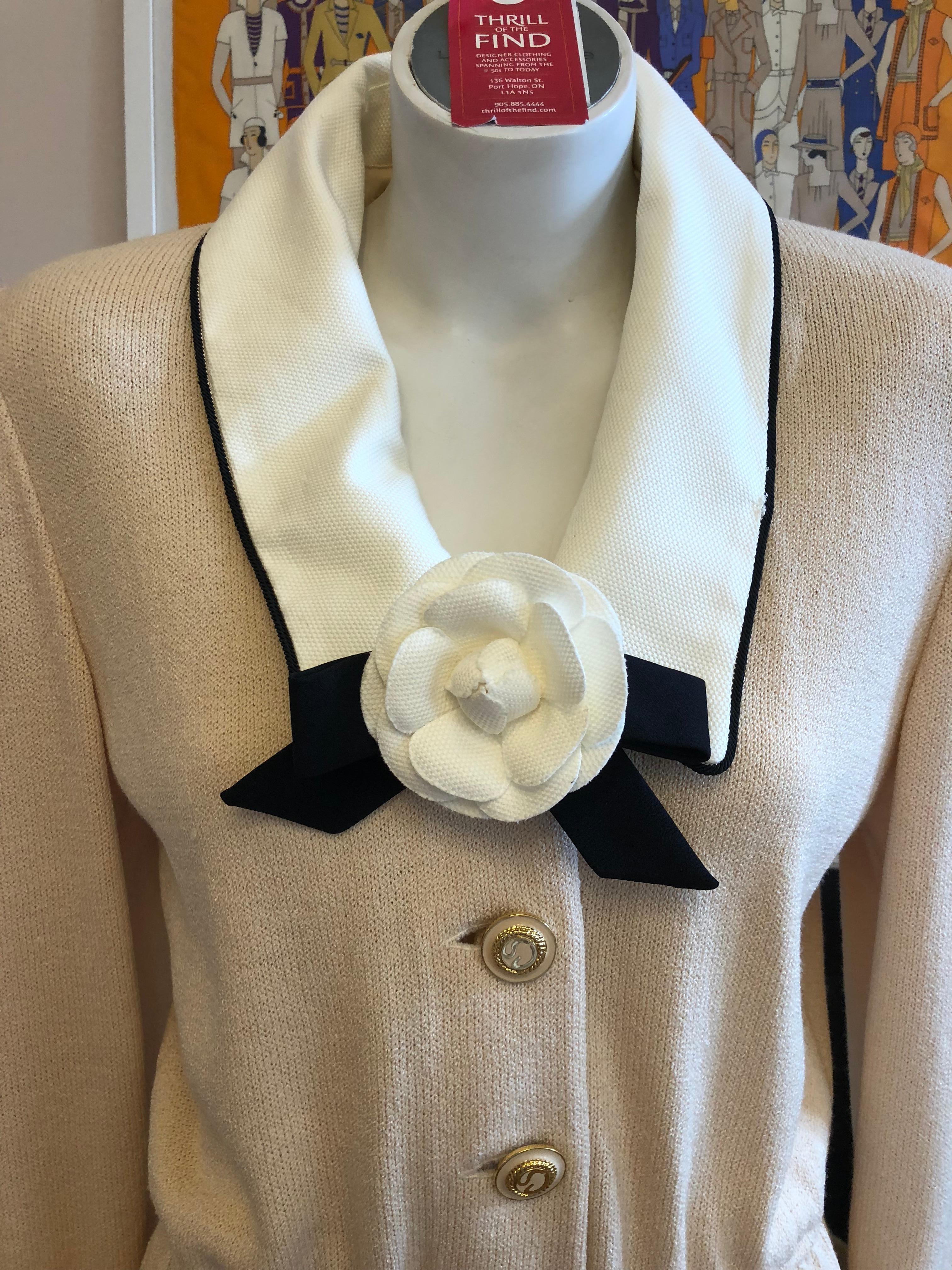 Lovely beige with a pink tinge Santana knit dress w/white with black trim pique cotton removable collar and cuffs. This dress also has a removable camellia brooch; three beautiful buttons at the front, and is made with 80% wool and 20% rayon.

St