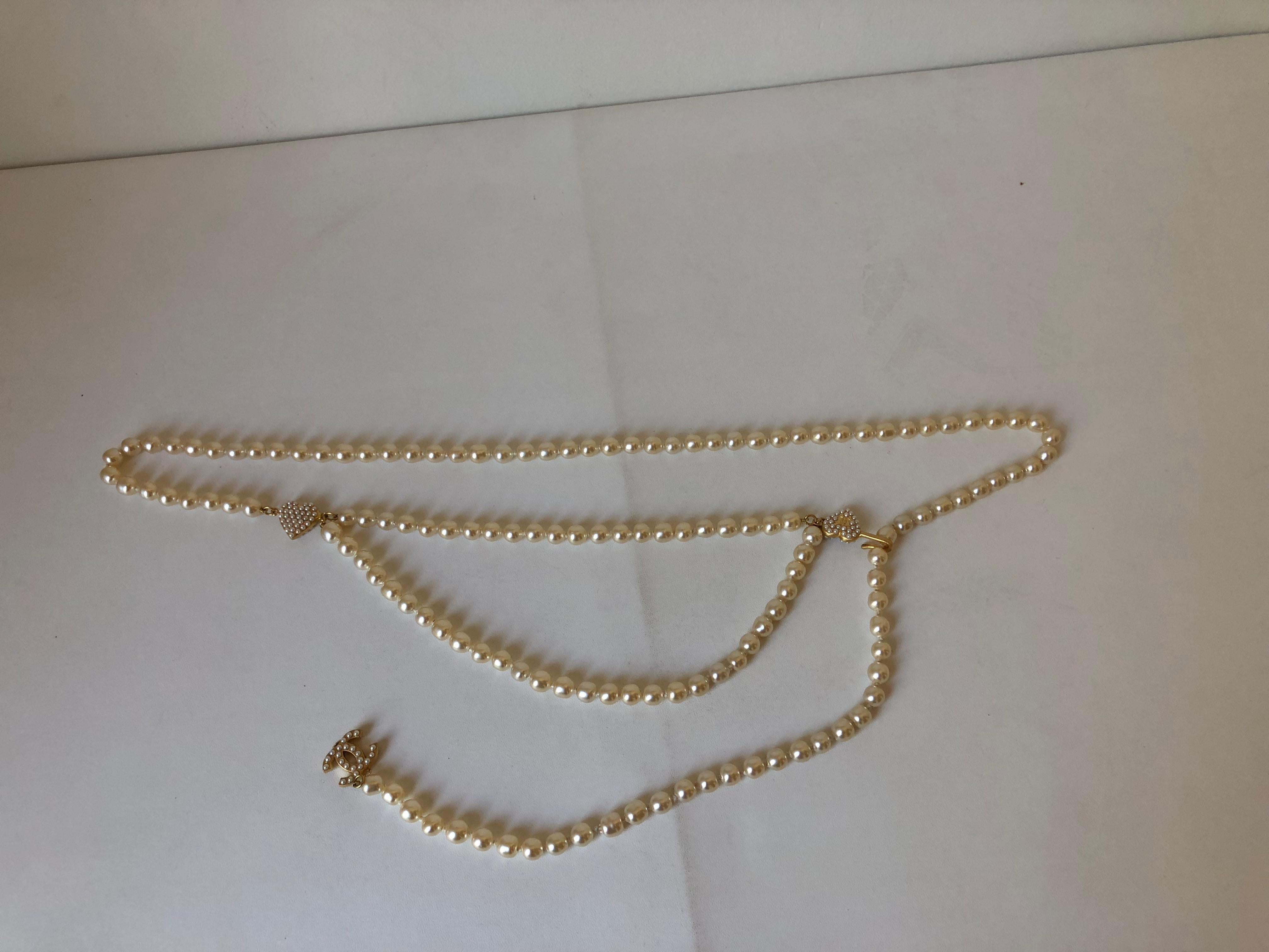 Ivory pearl Chanel belt with interlocking CC charm, gold tone 
hardware and hook closure.
Can be used as necklace.