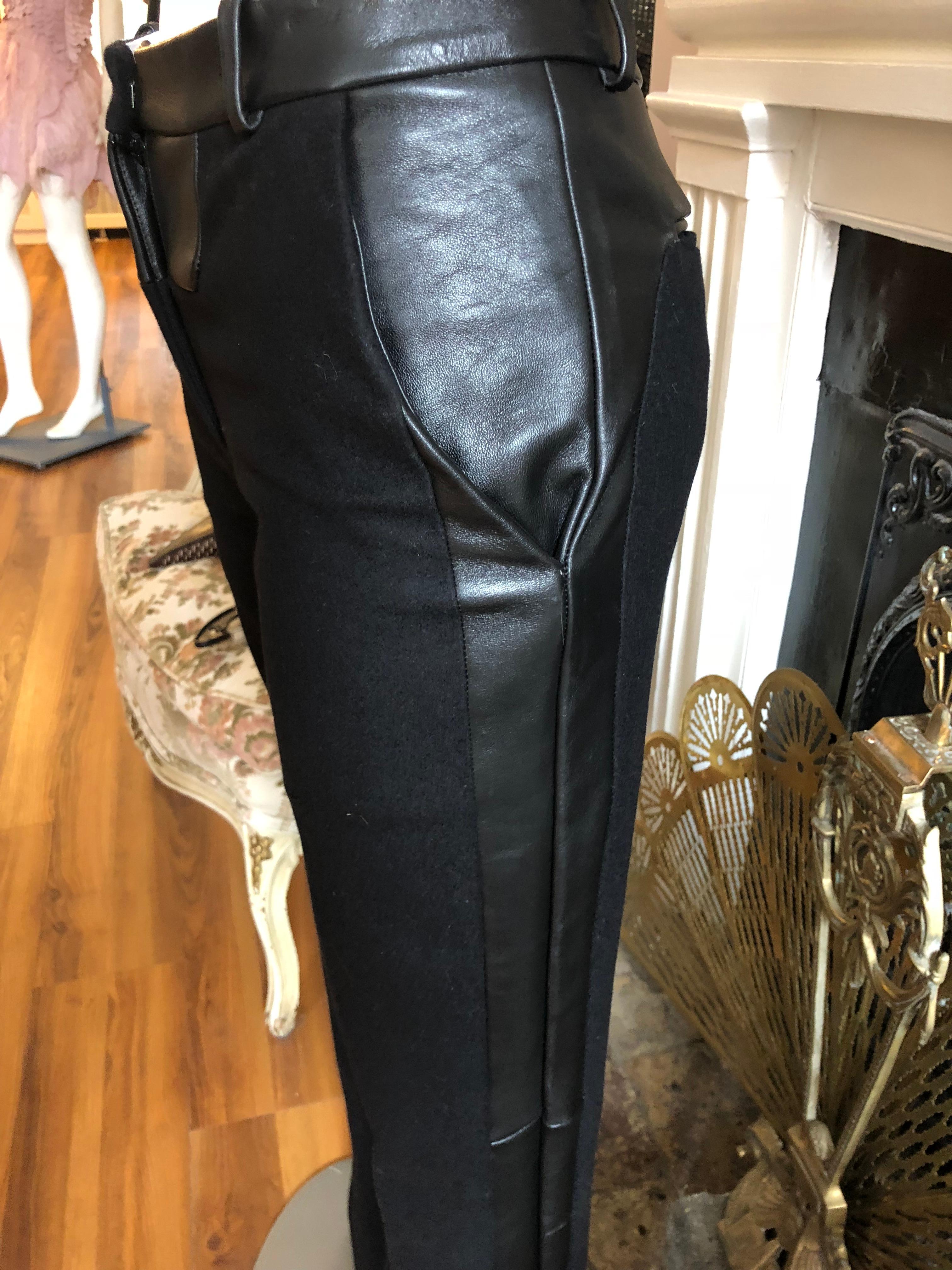 We believe these were a runway piece and are beautifully tailored. The straight leg pants are mid-rise; have lambskin side panels on each leg and hems, as well as at the waist and slit pockets. Closure is at the middle front with a zip and eye and