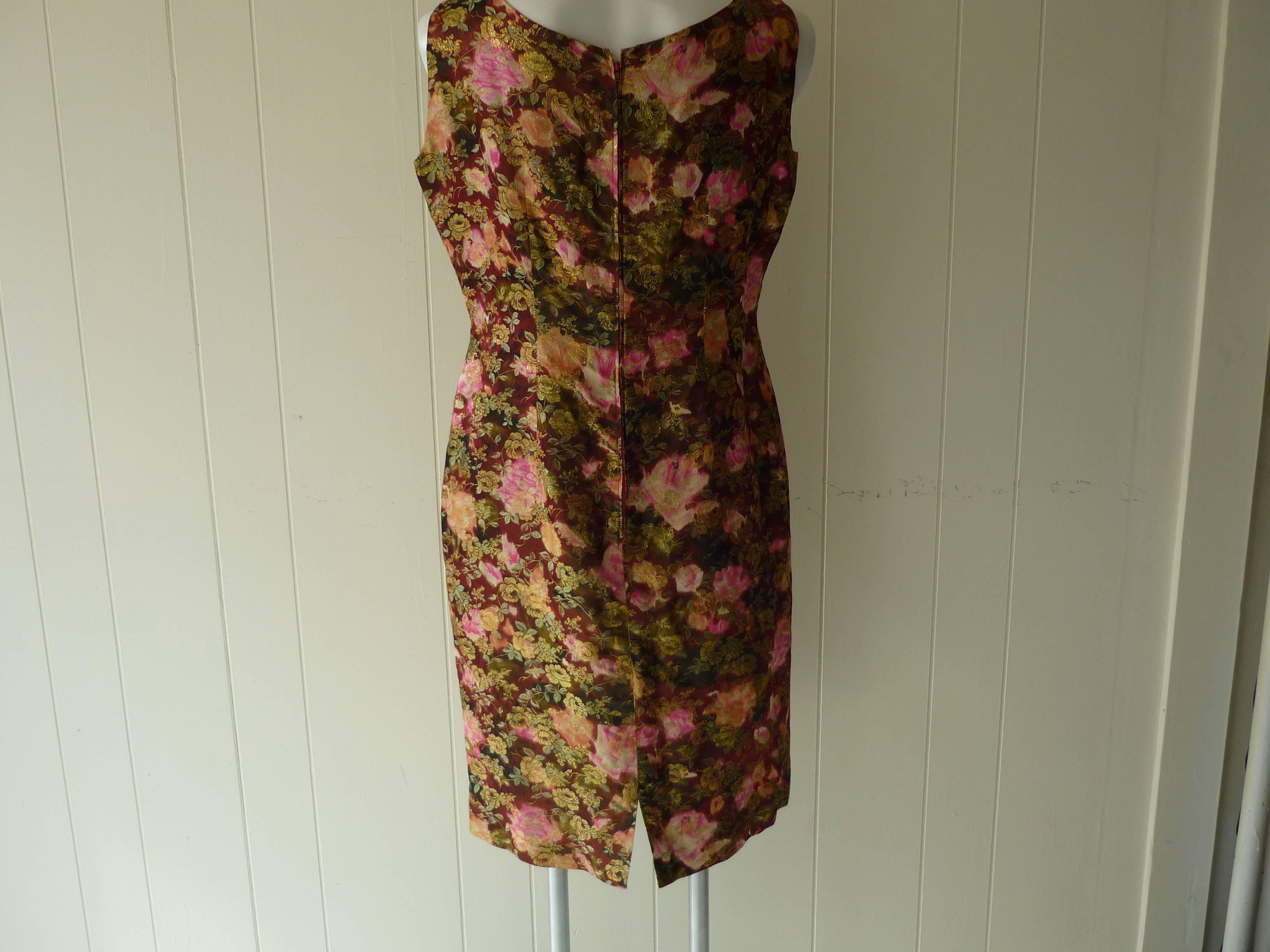 Lovely dress with pink and orange roses, green leaves, some brown and overlayed with gold accents.

Closure is by way of a zipper in the back, and the lining is burgundy.