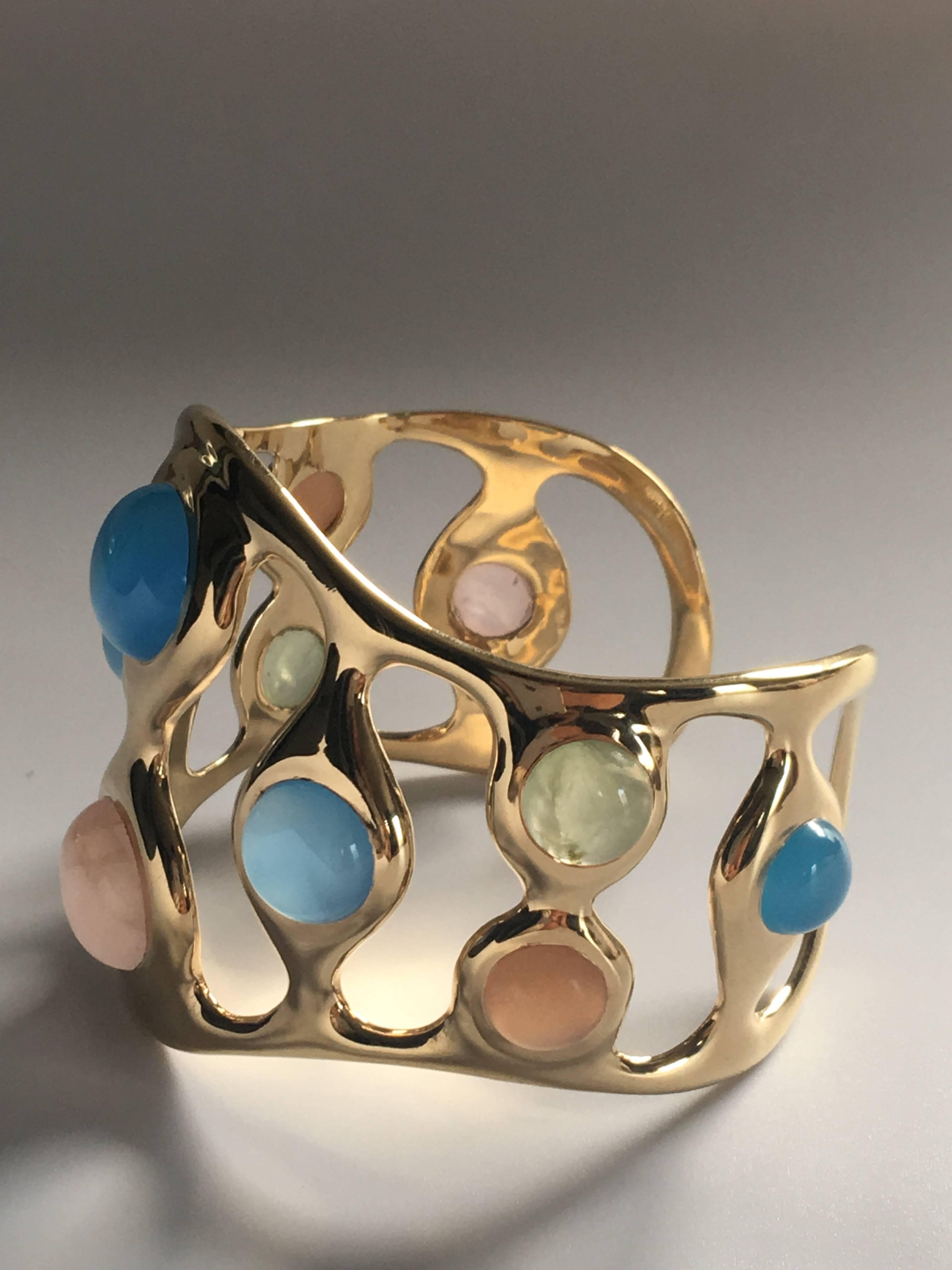 Curvaceous and undulating tactile bracelet, smooth to the touch with multicoloured cabochon opals  in various sizes. It is open at the back making it easy to wear.

Rhodium coated silver with 2.5 microns 18kt. gold vermeil