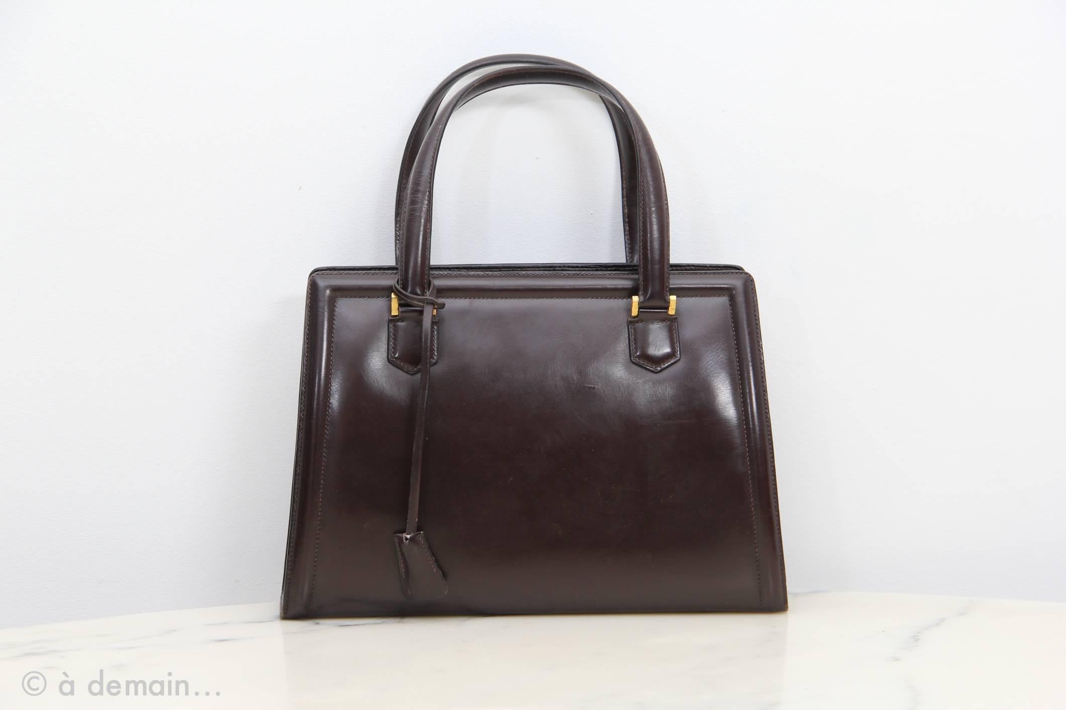 Brown leather vintage bag by Hermès Paris with gold plated hardware.
Three pockets and the middle one has a lock. Key available. 

Good condition with some leather wears of use. 
Height without handles: 21 cm
Height with: 33 cm
W: 29,5 cm
D: