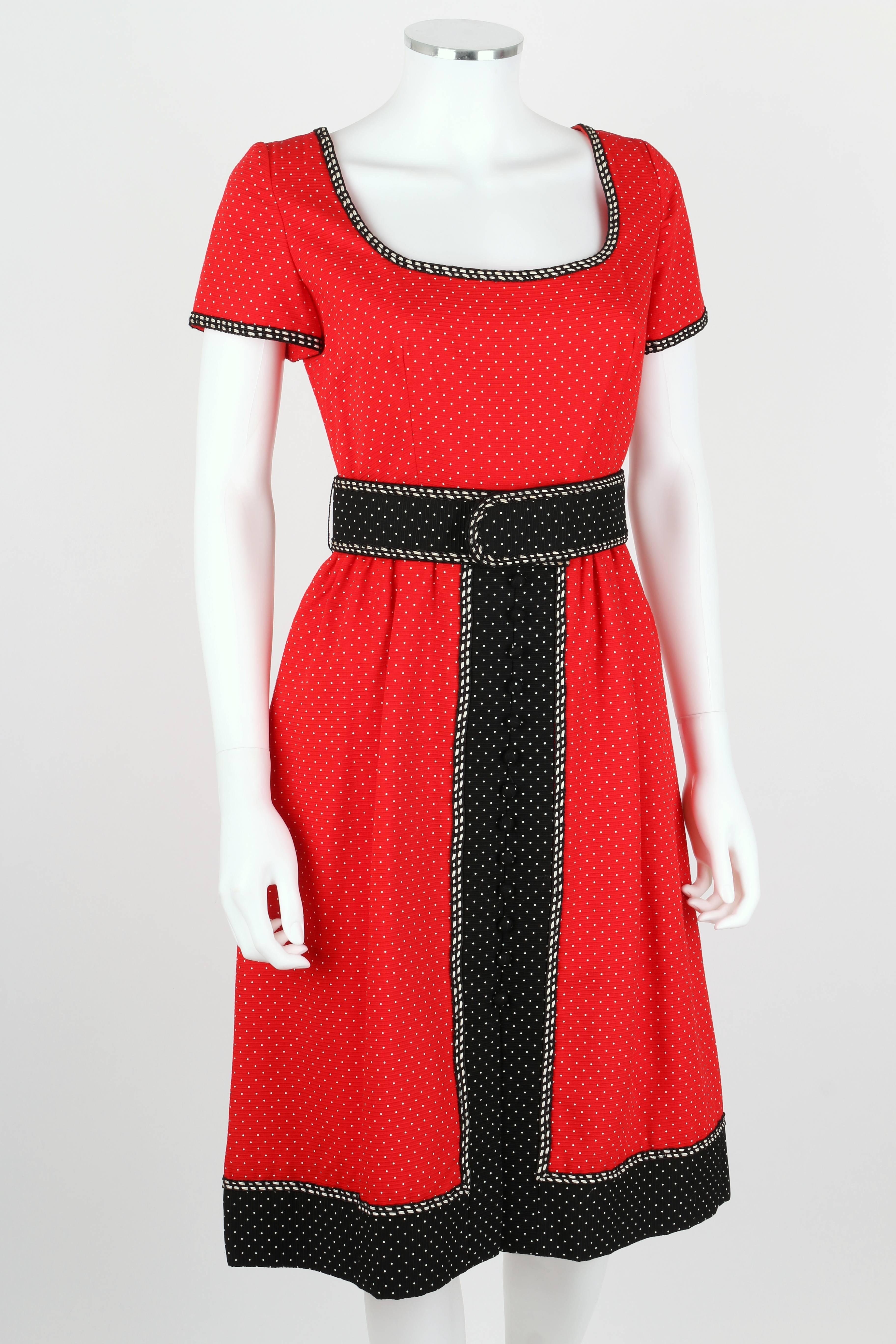 Rare 1960's early Oscar de la Renta boutique red, black, and white polka dotted dress. Black and white corded trim. Short sleeves. Low scoop neckline. Button detail at front of skirt. Dress zips at center back. Lined. Matching belt. Please note that