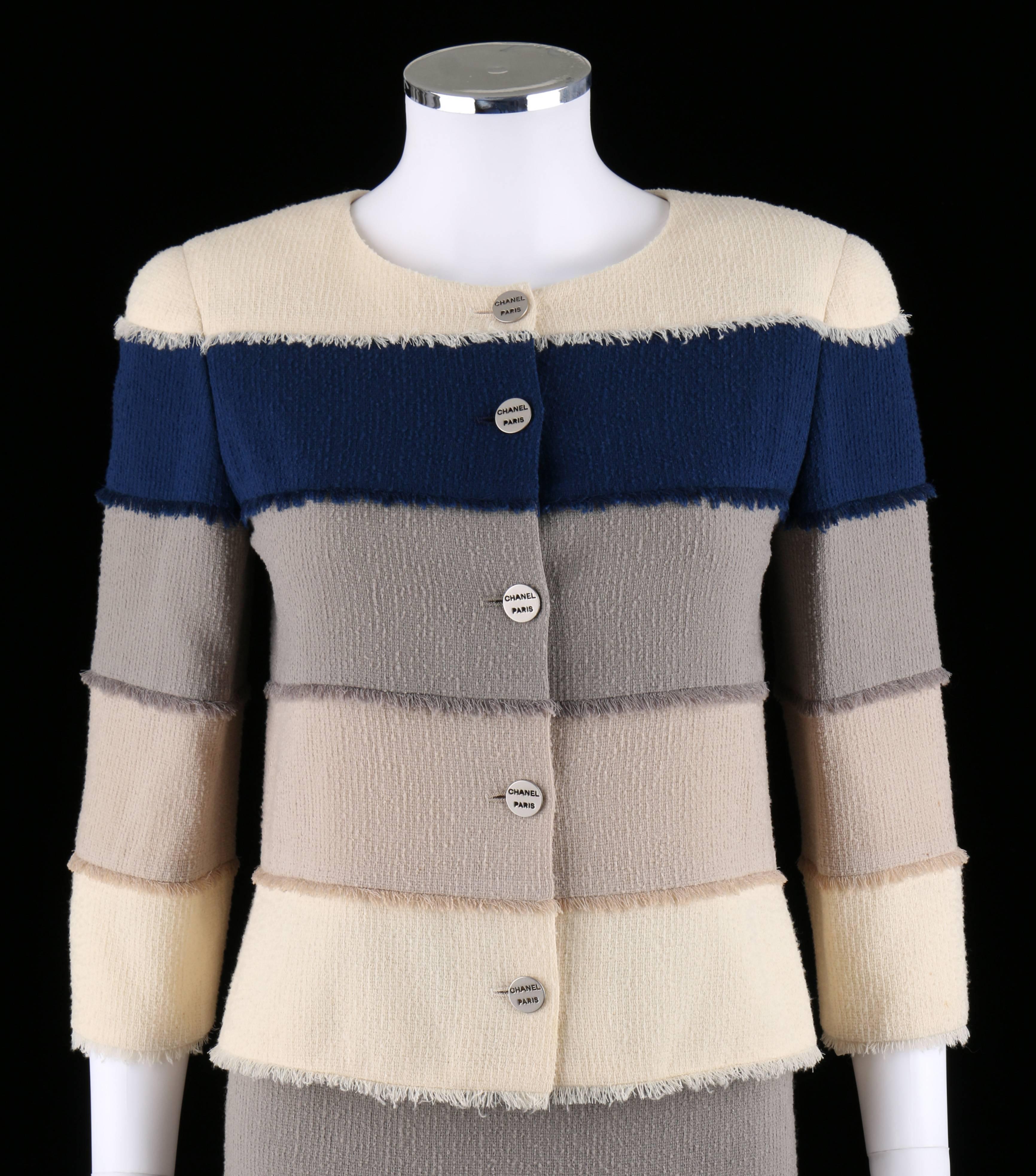 Costume deux pièces en tweed de laine bouclé de la collection Chanel Cruise 2000. La veste est de couleur ivoire, marine, beige et taupe avec des franges. manches 3/4. Se ferme sur le devant avec des boutons argentés 