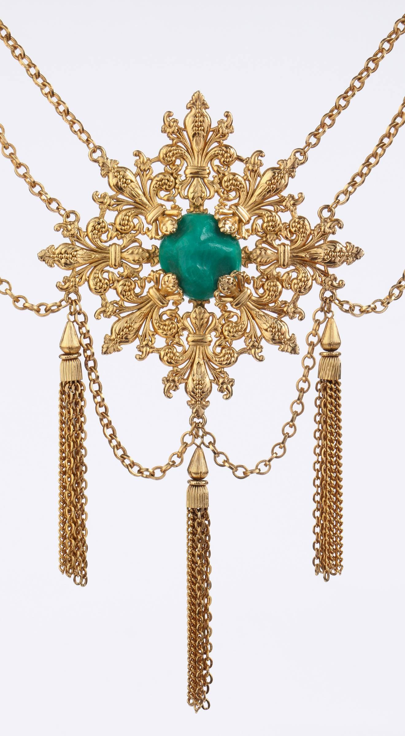 Vintage 1970s Napier gold tone sculptural Baroque revival Fleur de Lis pattern medallion with large center emerald colored faux-stone.  Medallion measures 4.5