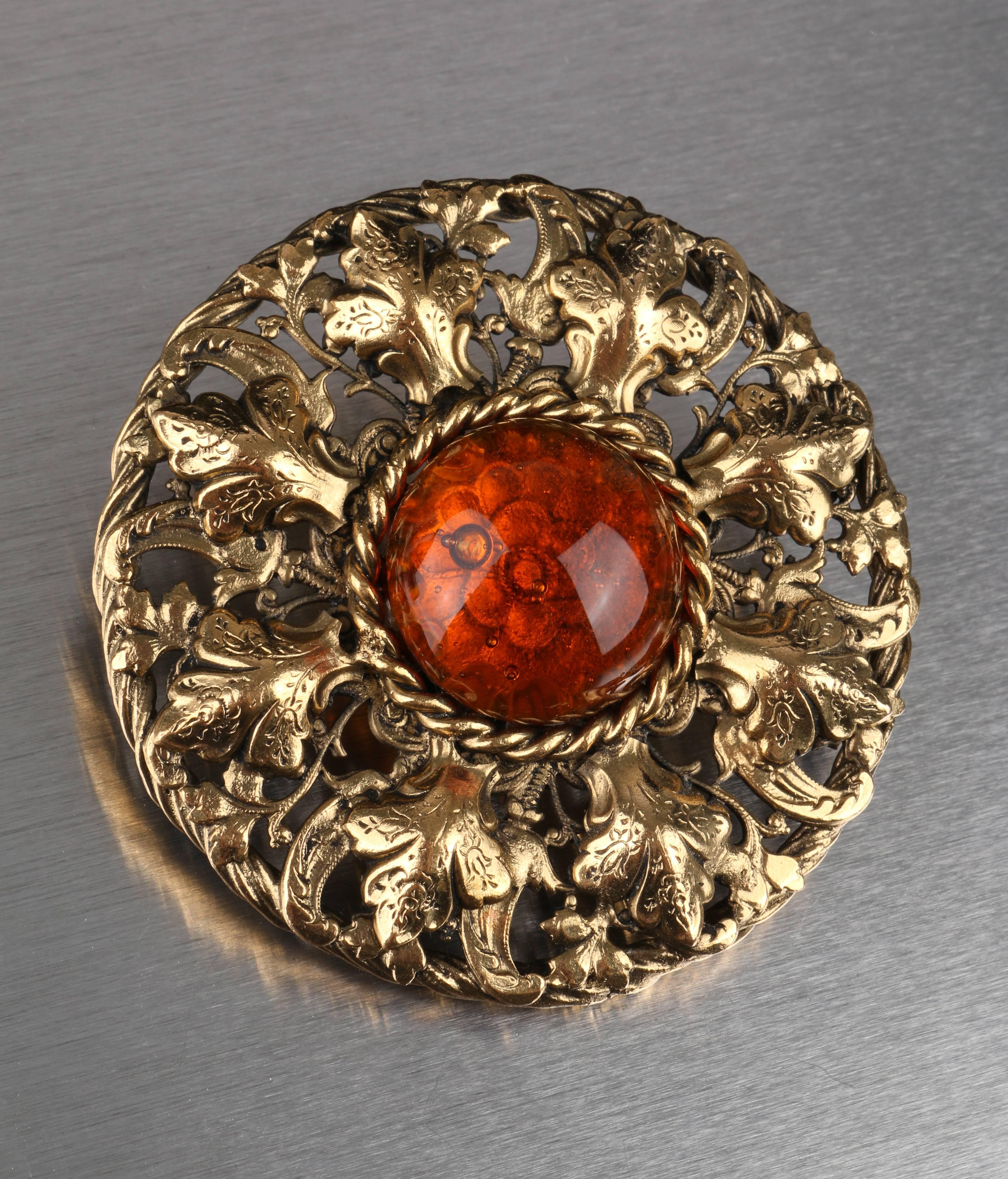 Chanel Autumn/ WInter 1995 large gold-tone metal brooch with central amber-colored Gripoix poured glass cabochon (measures approximately 33 mm). Floral camellia detail is visible through the cabochon. Back pin closure. Back hook allows brooch to be