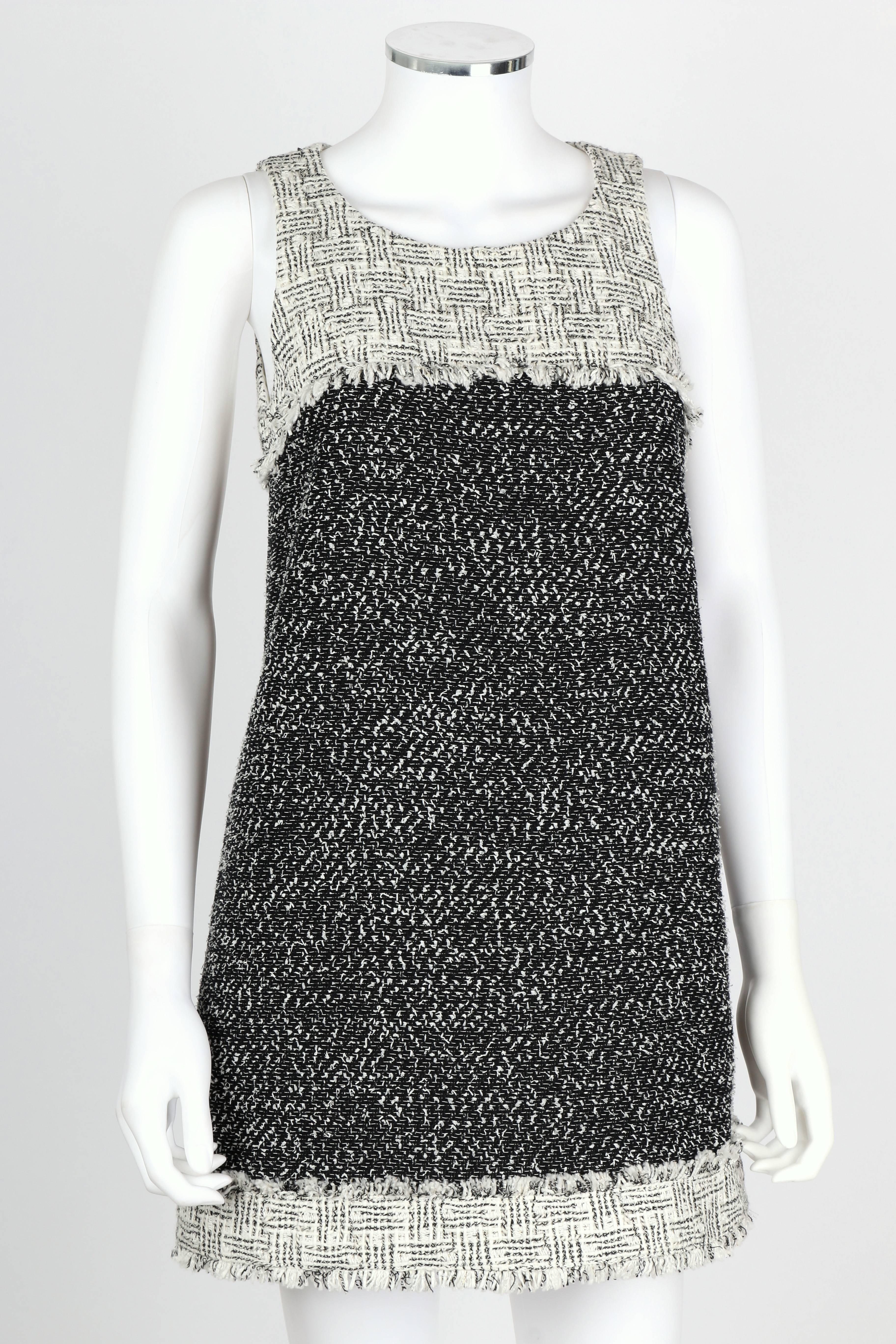 New with original tags attached. Chanel Spring 2014 black and white tweed / boucle mini shift dress. Sleeveless with a scoop neckline. Open thin keyhole upper back closes at back of neck with single hook/eye. Skirt closes at back with three snaps.