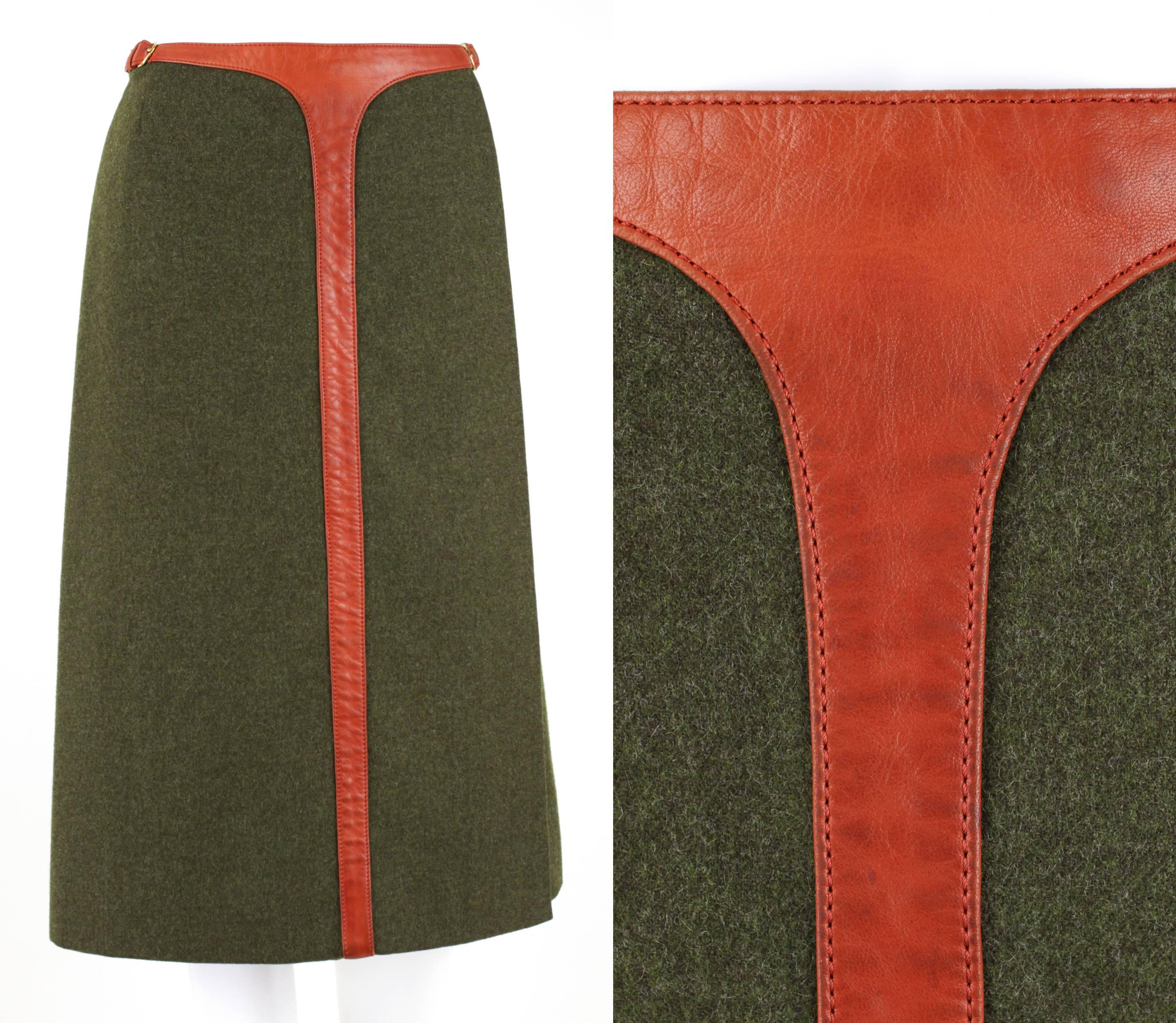 Vintage c.1970's Hermes Sport olive green wool wrap skirt. Orange-brown genuine lambskin trim around waist and down center of skirt. Wrap secures with buckle, snap and hook/eyes on left side waist. Knee length. Fully lined. Marked Fabric Content: