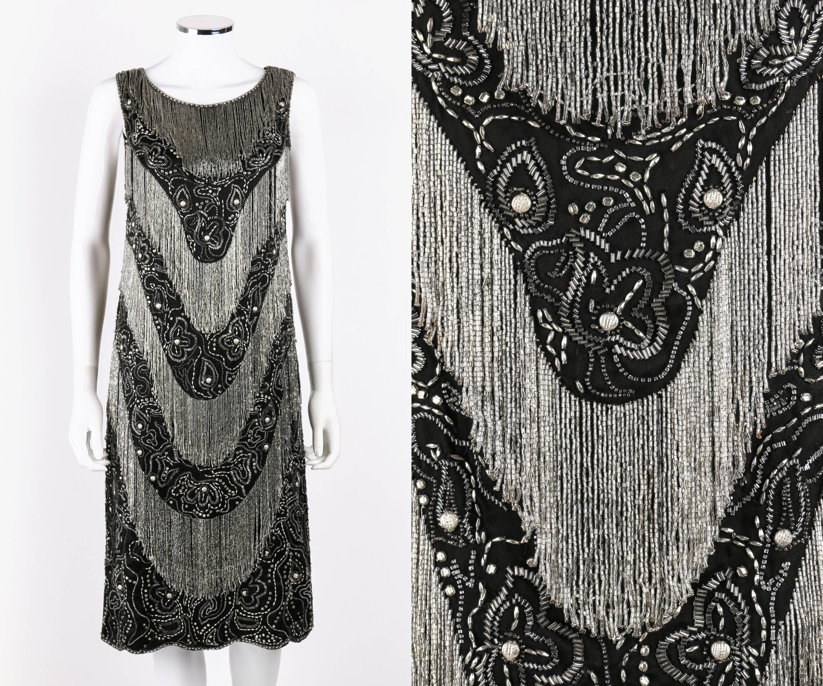 Couture c.1920's vintage black silk heavily beaded flapper evening dress. Tiered scooped transparent glass bead fringe detail on front and back. Beaded floral embellishment between fringe layers. Sleeveless. Scoop neckline. Knee length scalloped